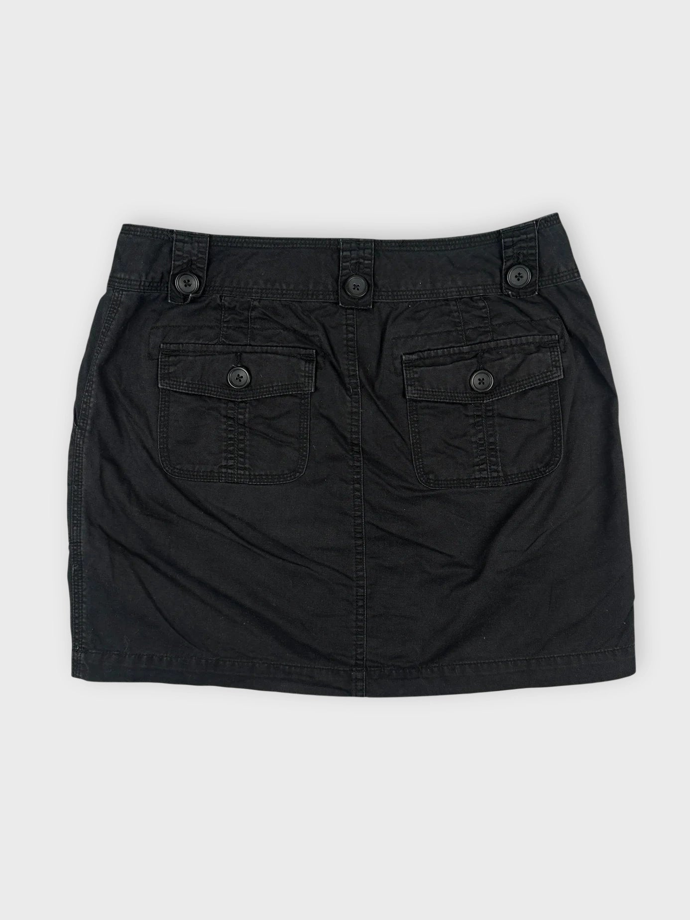 Back view of a black mini skirt featuring button details and two pockets.