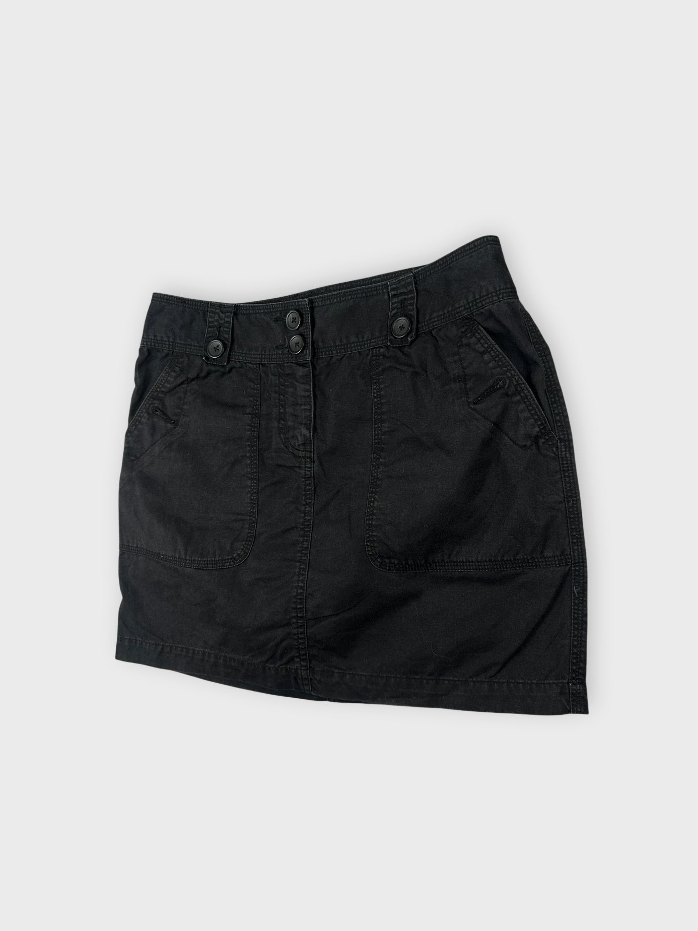Detail view of a black mini skirt with button details.
