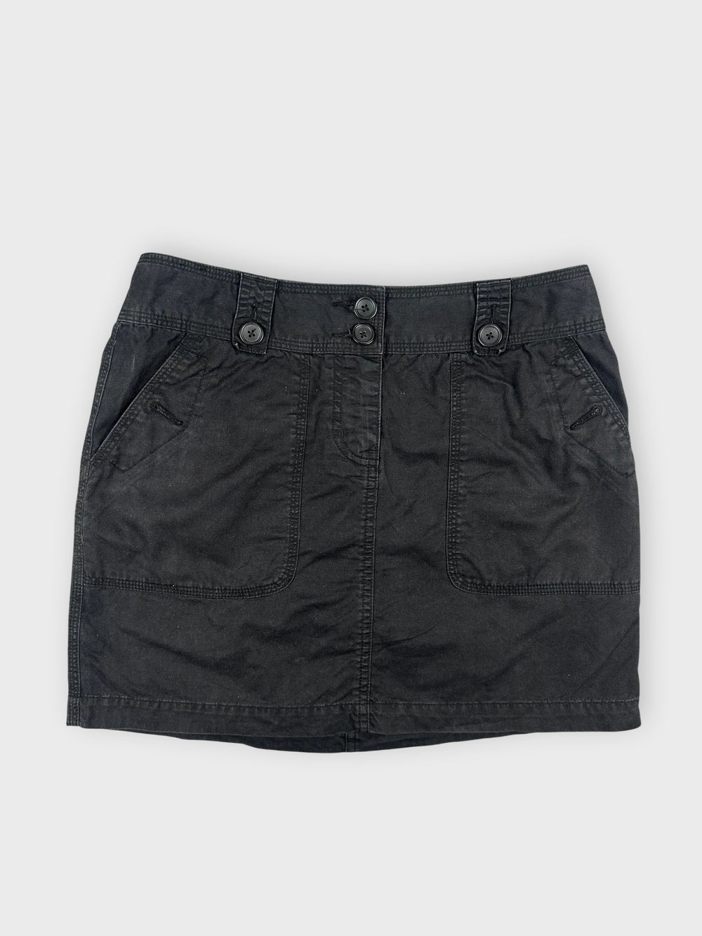 Chic black mini skirt front view with button details and two pockets.