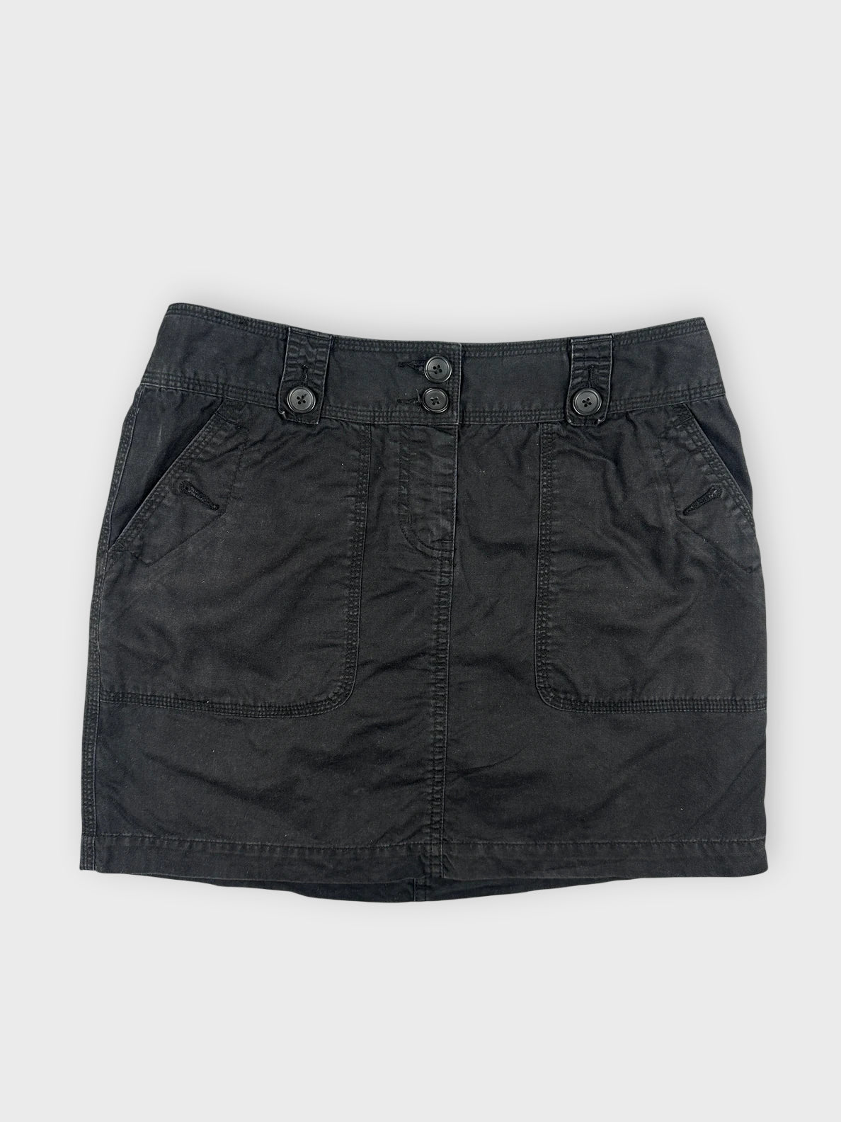 Chic black mini skirt front view with button details and two pockets.