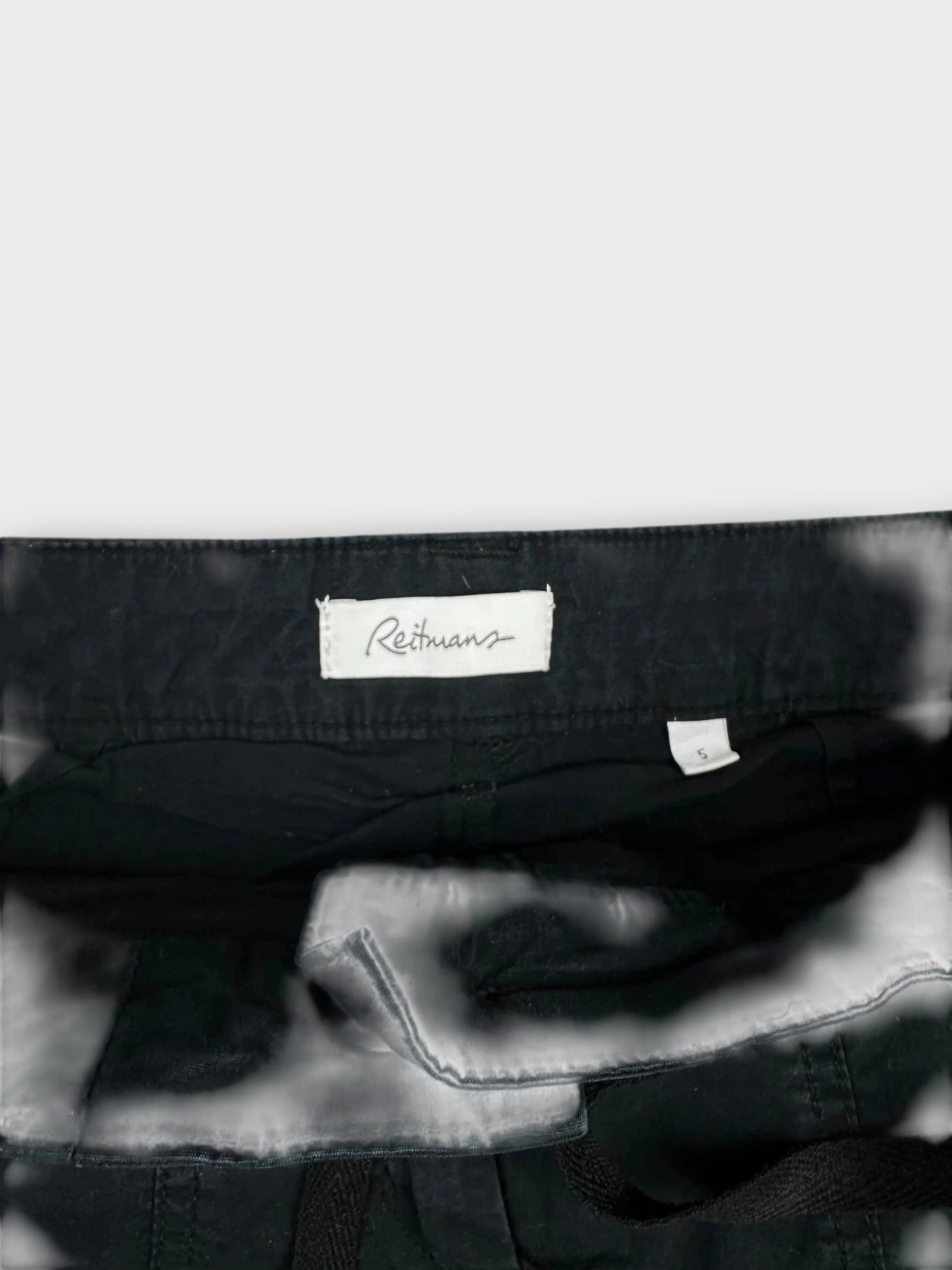 Detail view of a black mini skirt featuring side zipper details.