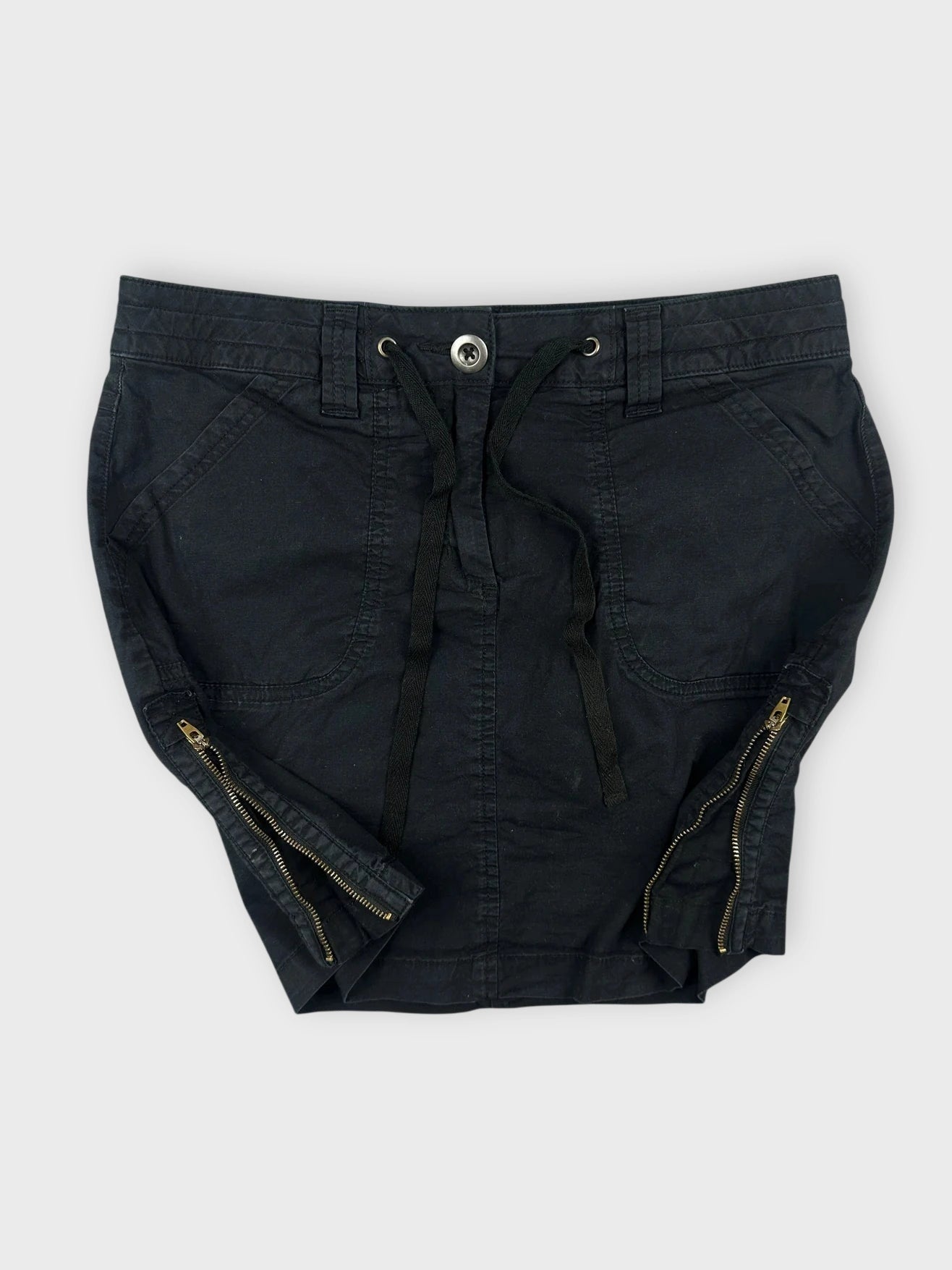 Detail view of a black mini skirt with side zipper details.