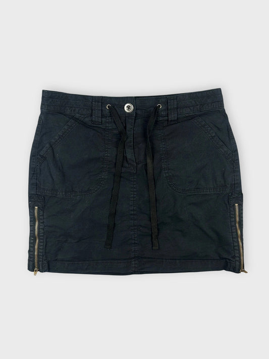 Front view of a black mini skirt featuring zipper details on the sides.