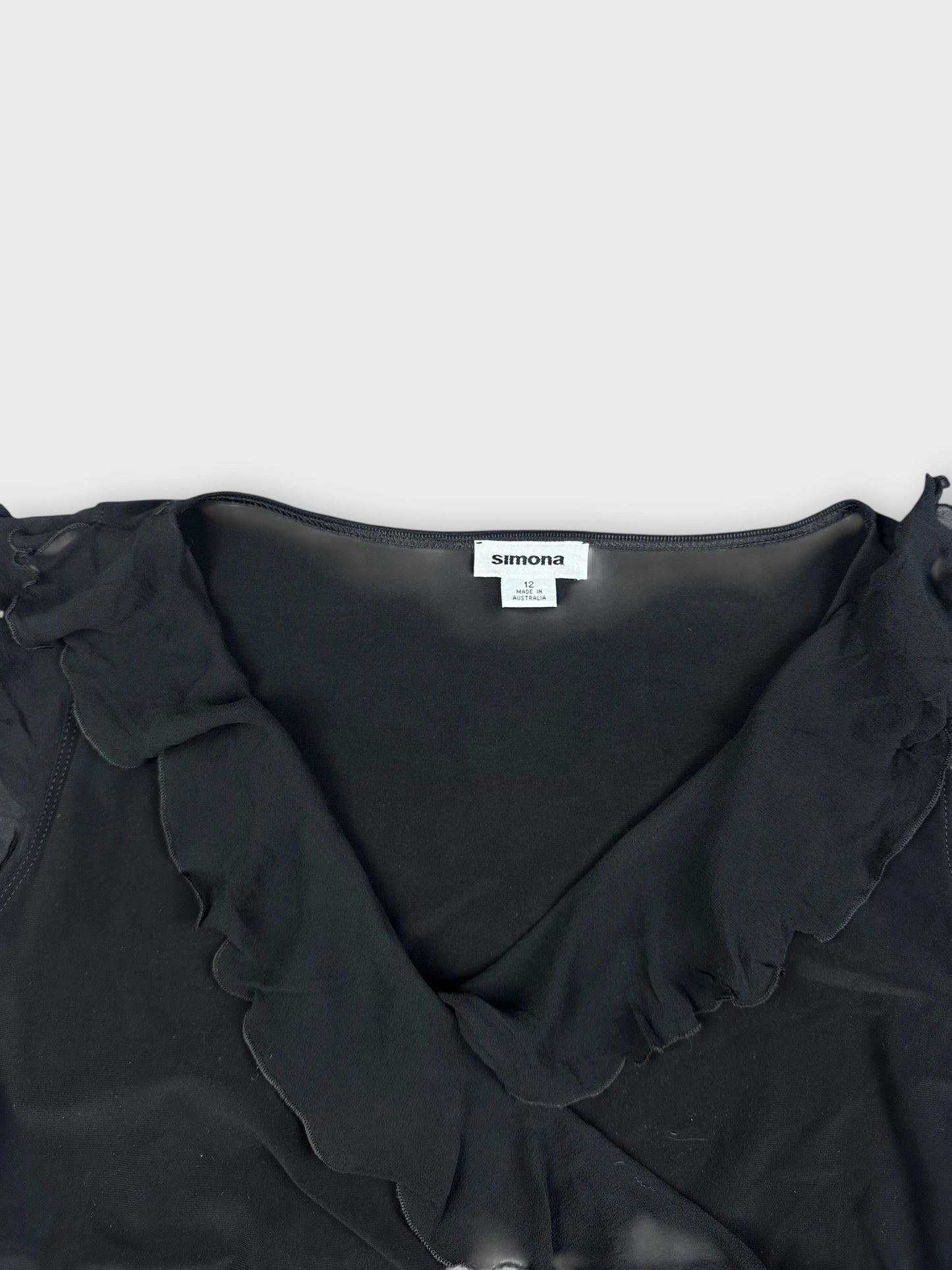 Detail view of a black ruffle wrap top featuring ruffled sleeves and V-neckline.