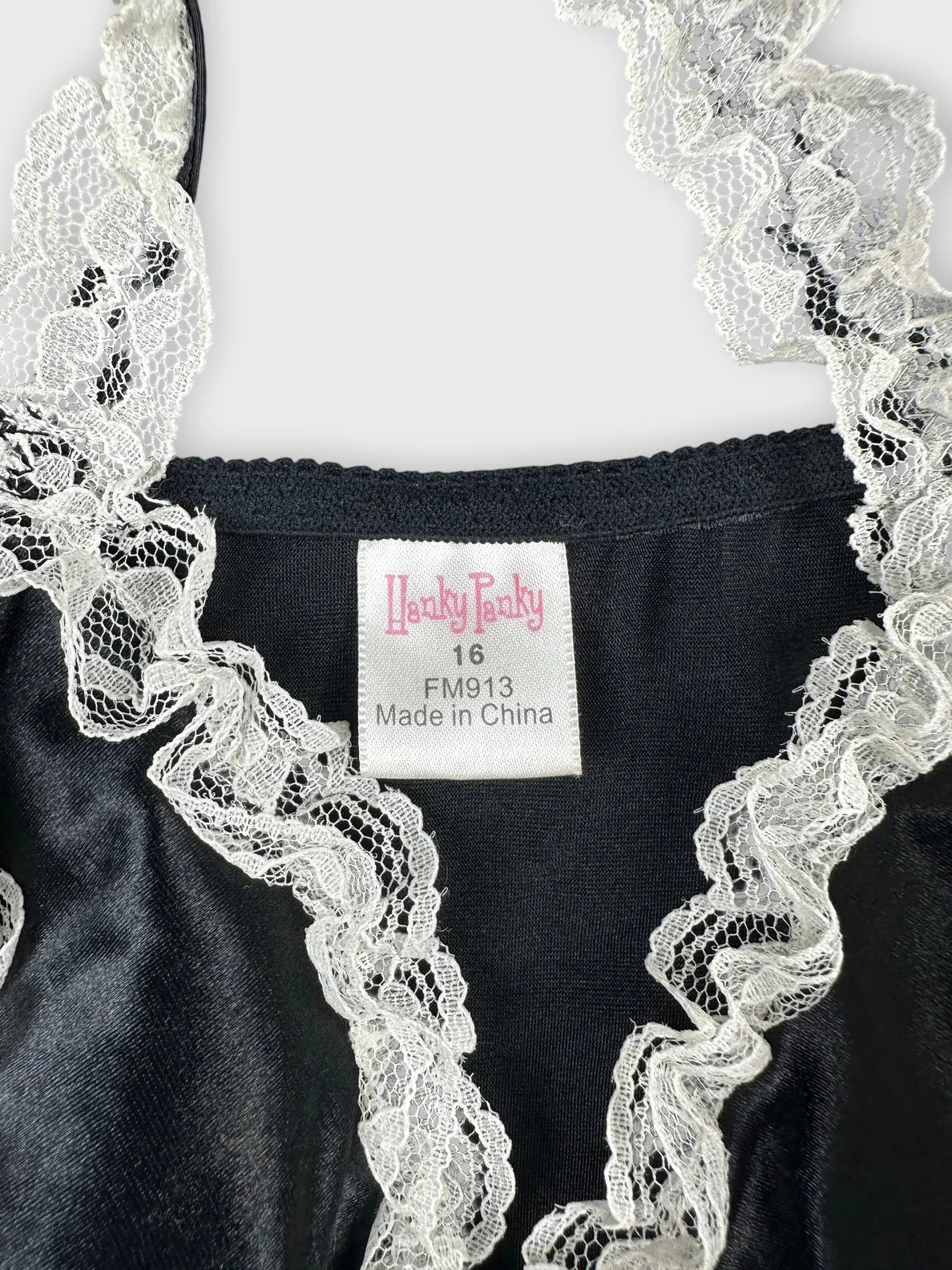 Detail view of a black satin top featuring white lace trim.