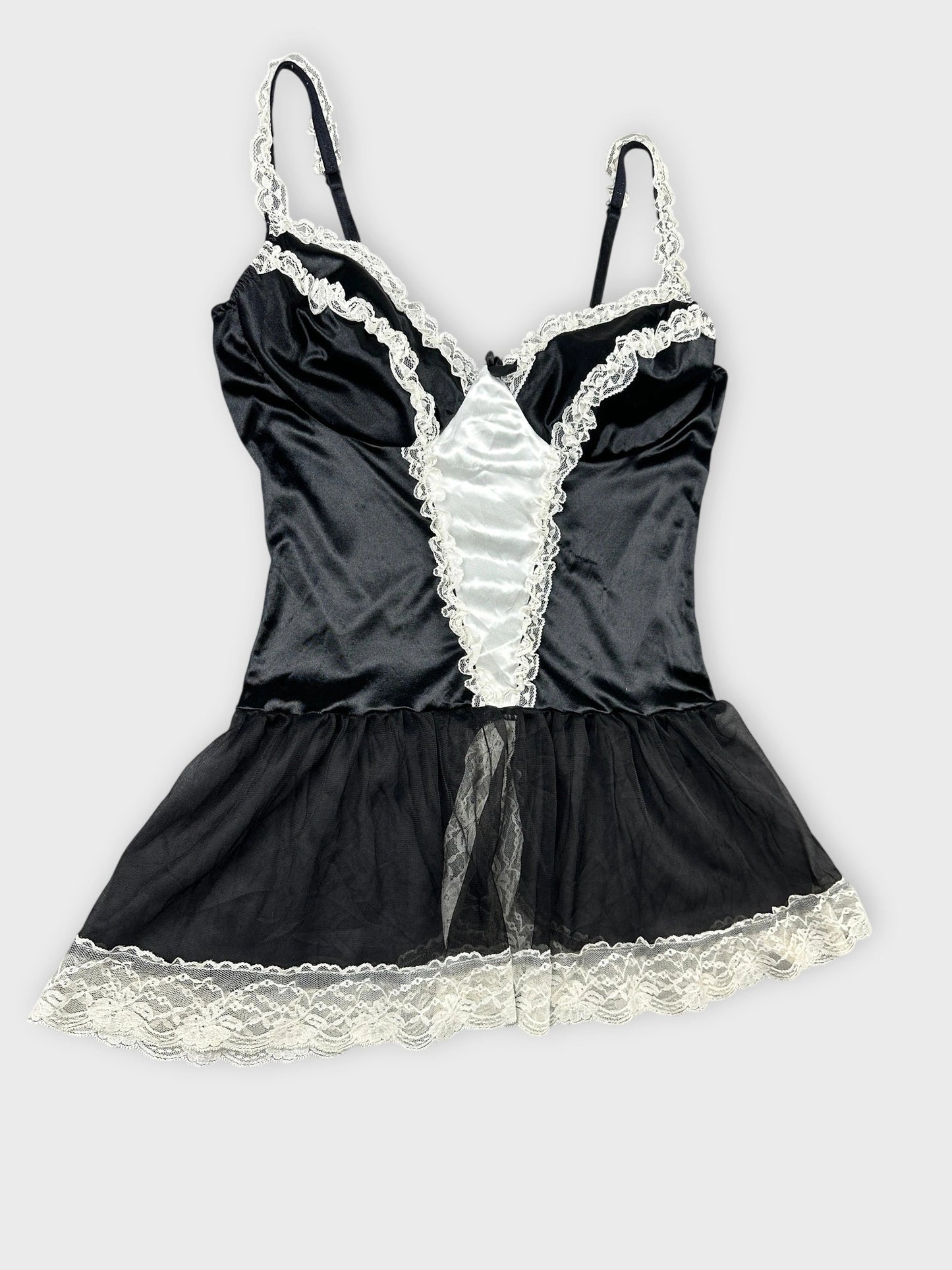 Detail view of a black satin top with white lace trim.