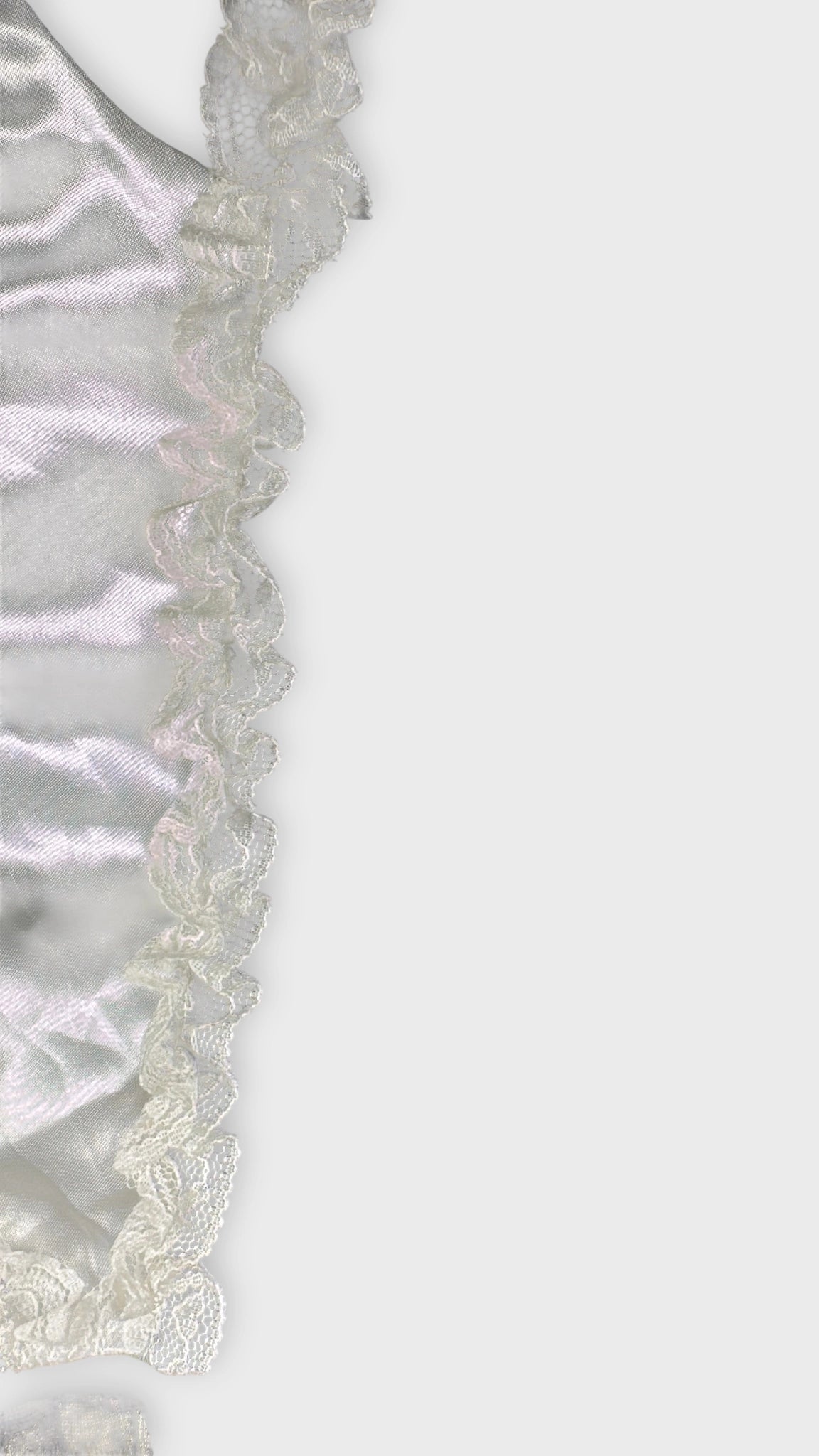 Detail view of a black satin top with white lace trim.
