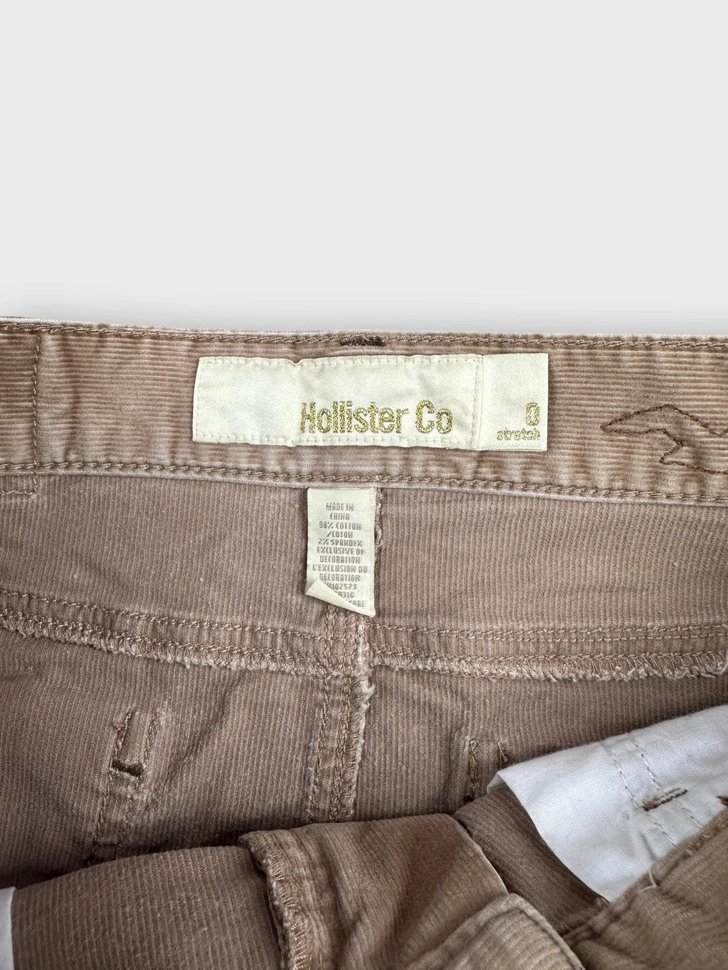 Detail view of a brown denim mini skirt with tag visible