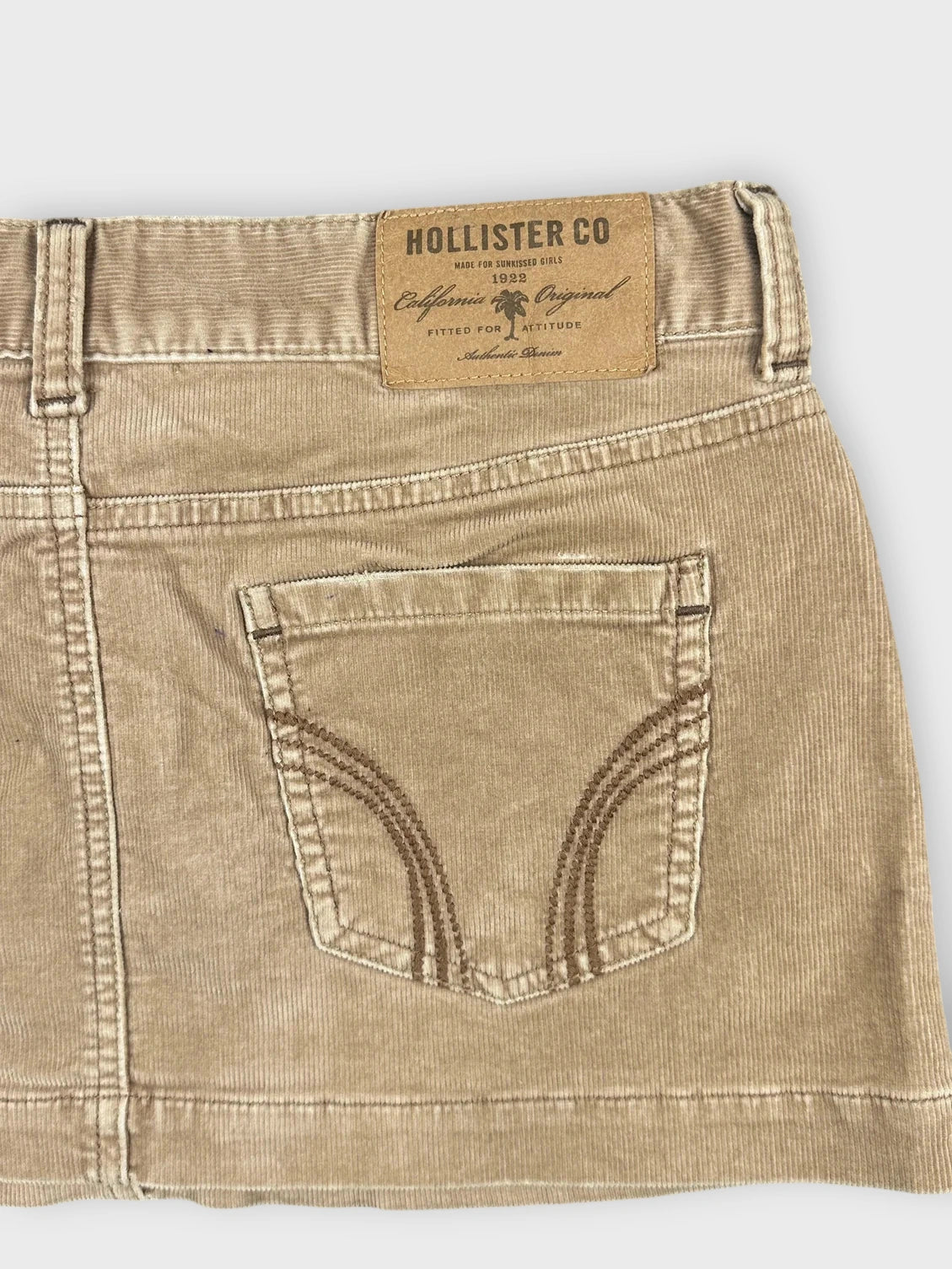 Detail view of a chic brown denim mini skirt with back pocket stitching.