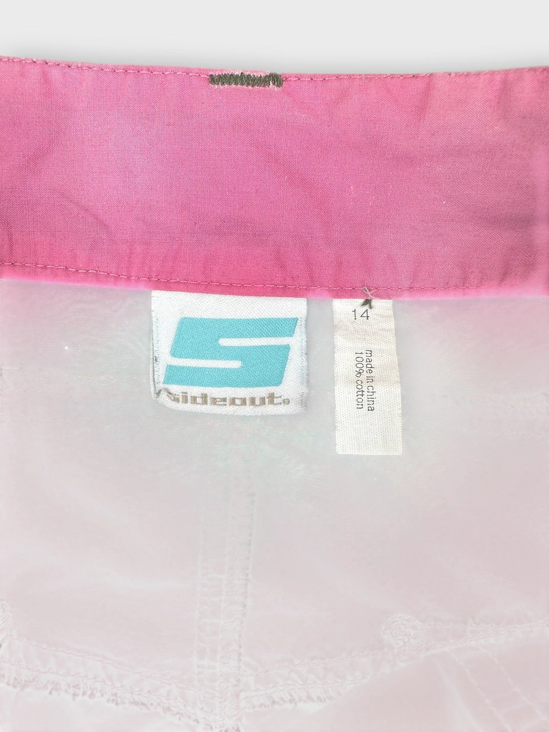 Detail view of a pink mini skirt zipper and label.