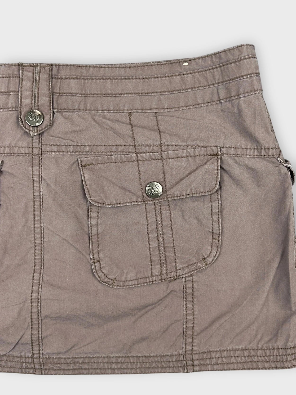Detail view of a brown mini skirt with front pockets.