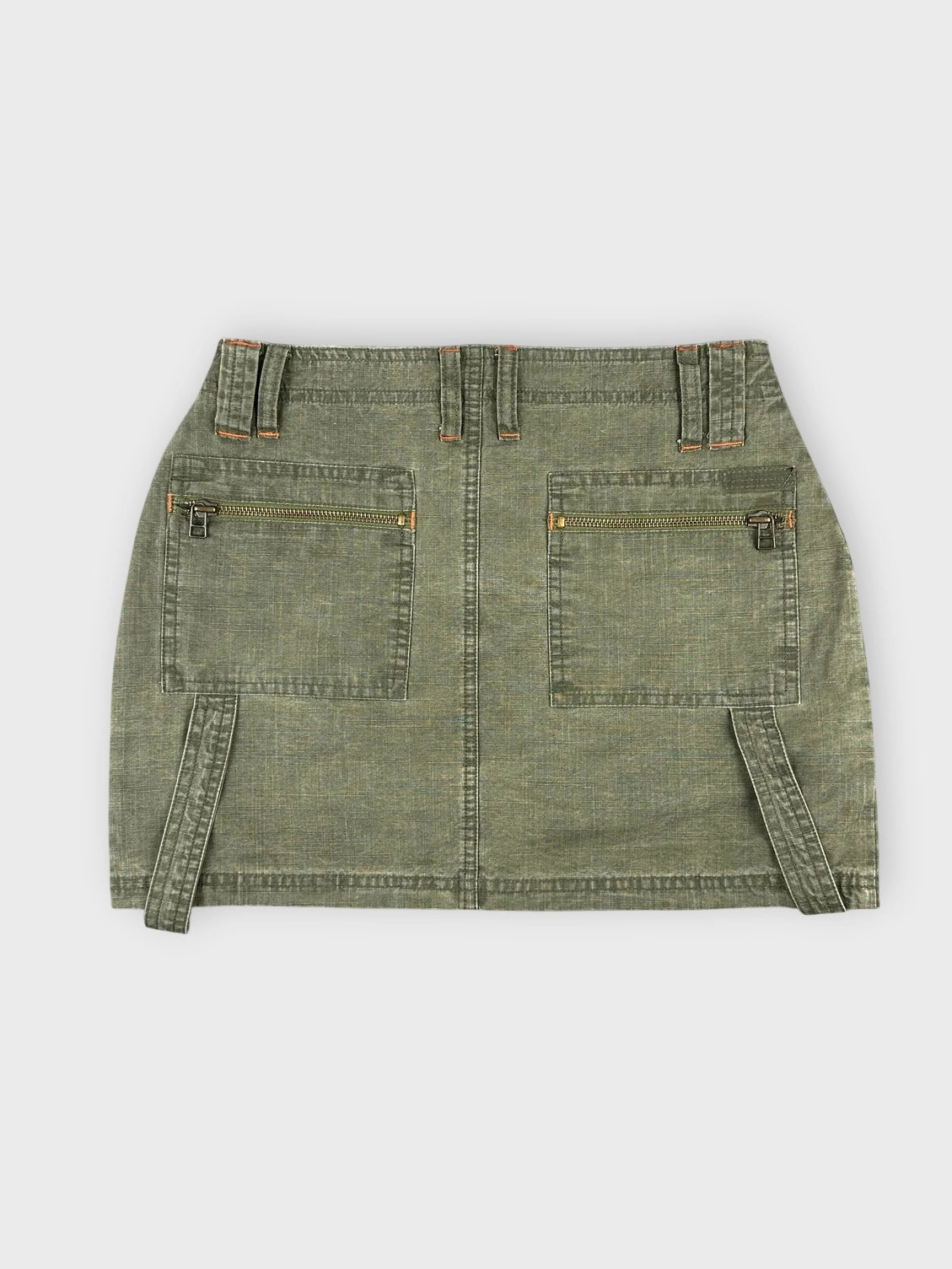 Back view of an olive mini skirt with side straps and two zip pockets.