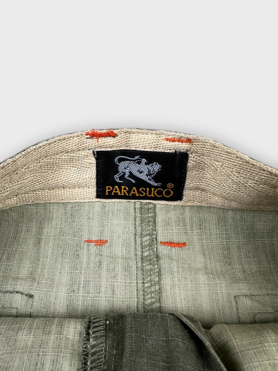 Detail view of olive mini skirt featuring unique side straps and branded label.