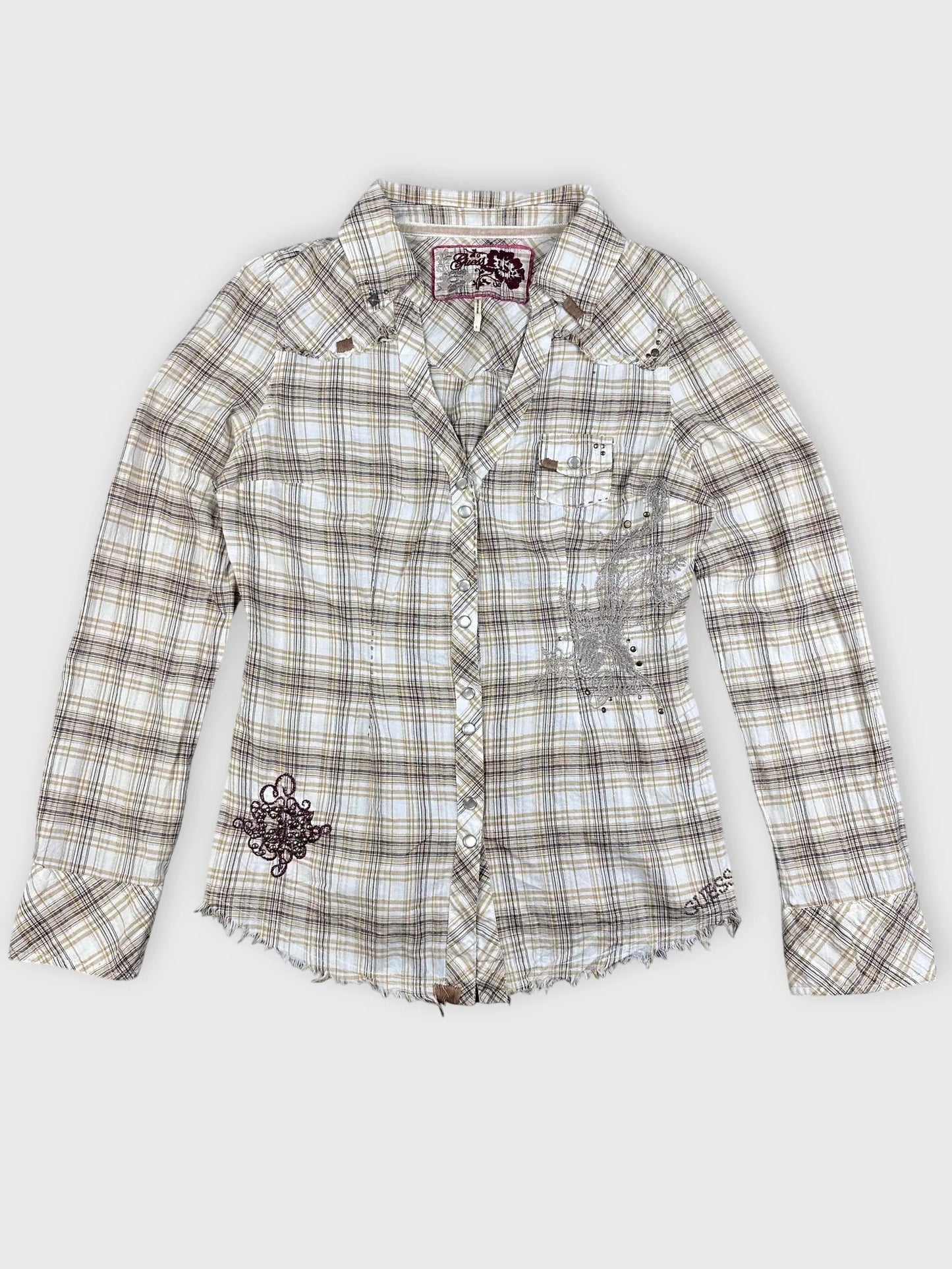 Detail view of plaid button-up shirt in beige with frayed hem.