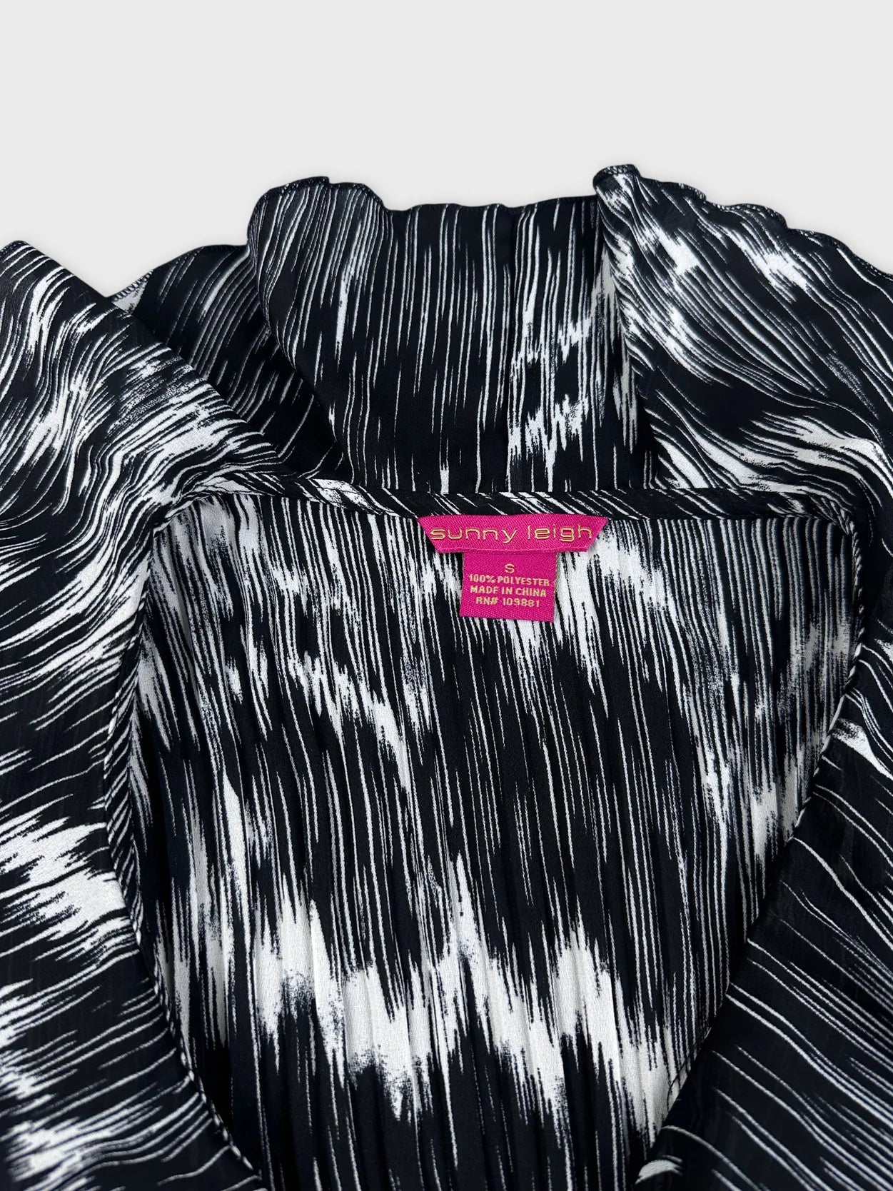 Detail view of black and white plissé top with ruffled shoulder detail.