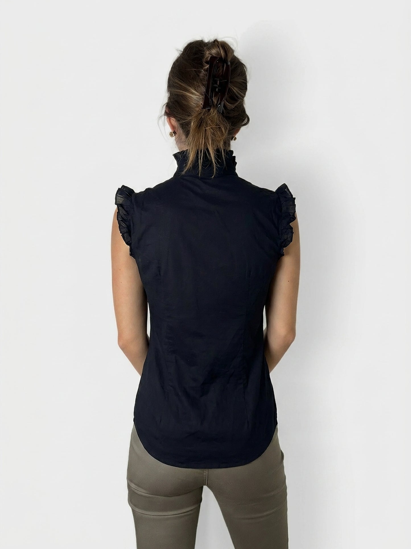 Back view of a black ruffled cotton top with a high collar.