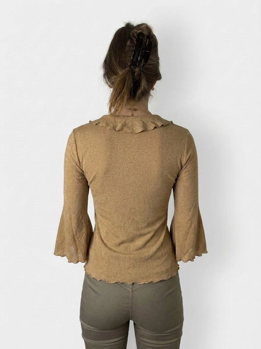 Back view of a warm beige long sleeve top with ruffled trim.