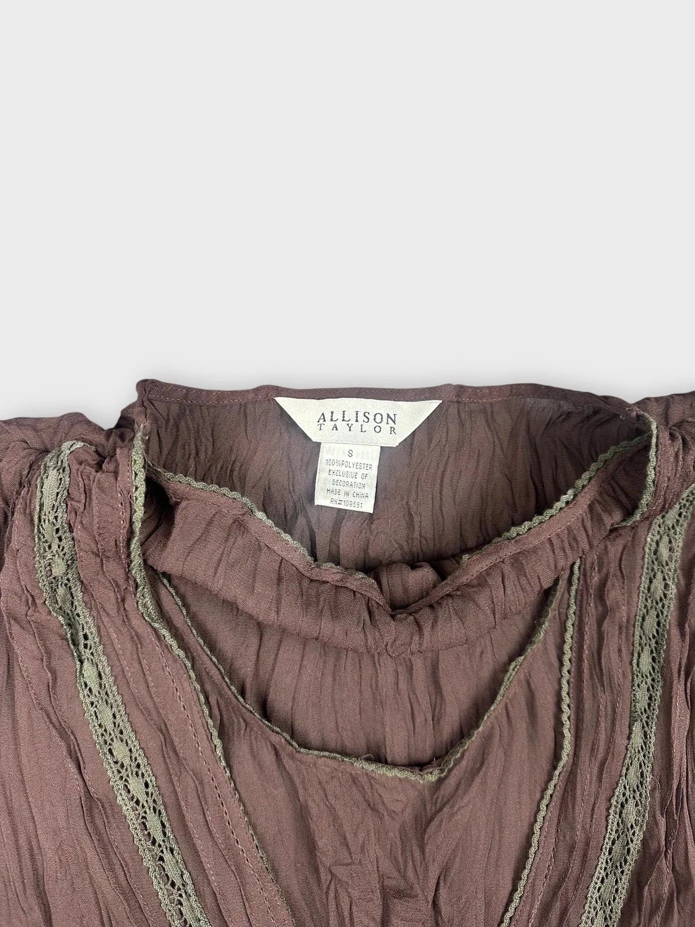 Detail view of a chocolate brown sheer top with lace trim embellishments.
