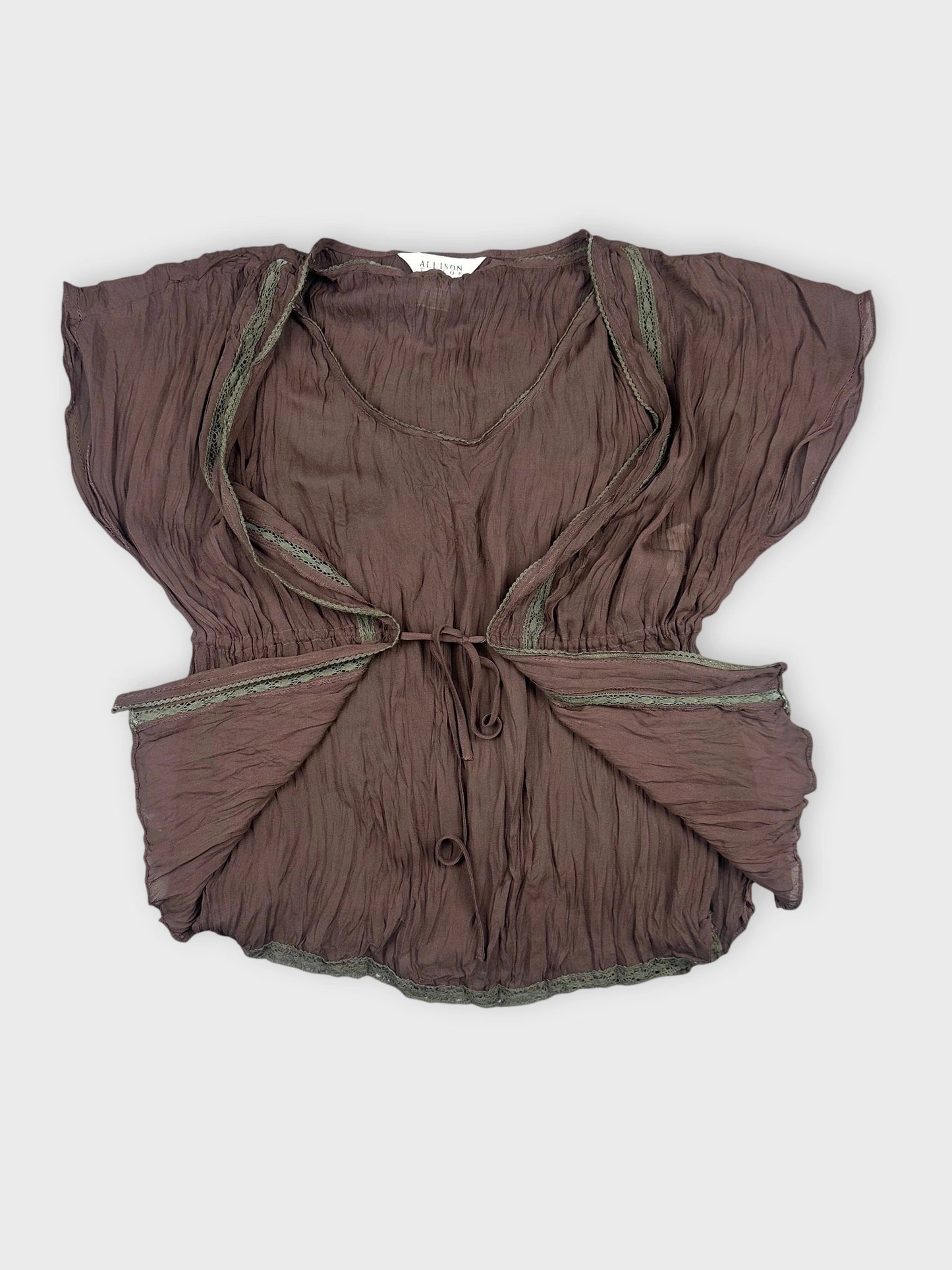 Detail view of a chocolate brown sheer ruffled top with lace trim.