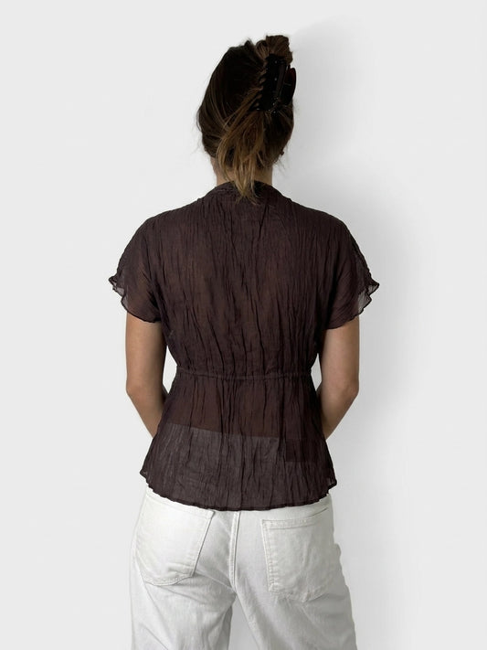 Back view of a sheer brown ruffled top with tie detail.