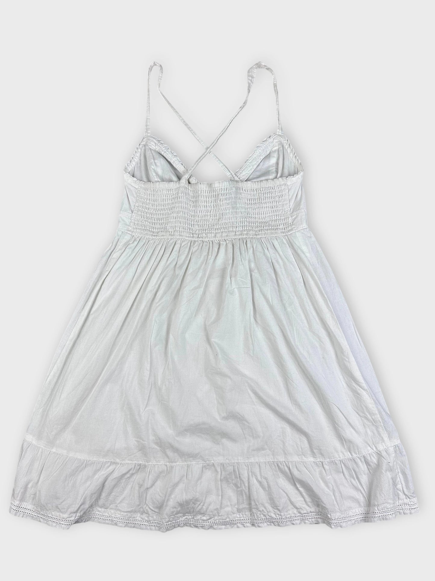 Back view of a white cotton strap dress with smocked bodice and ruffled hem.