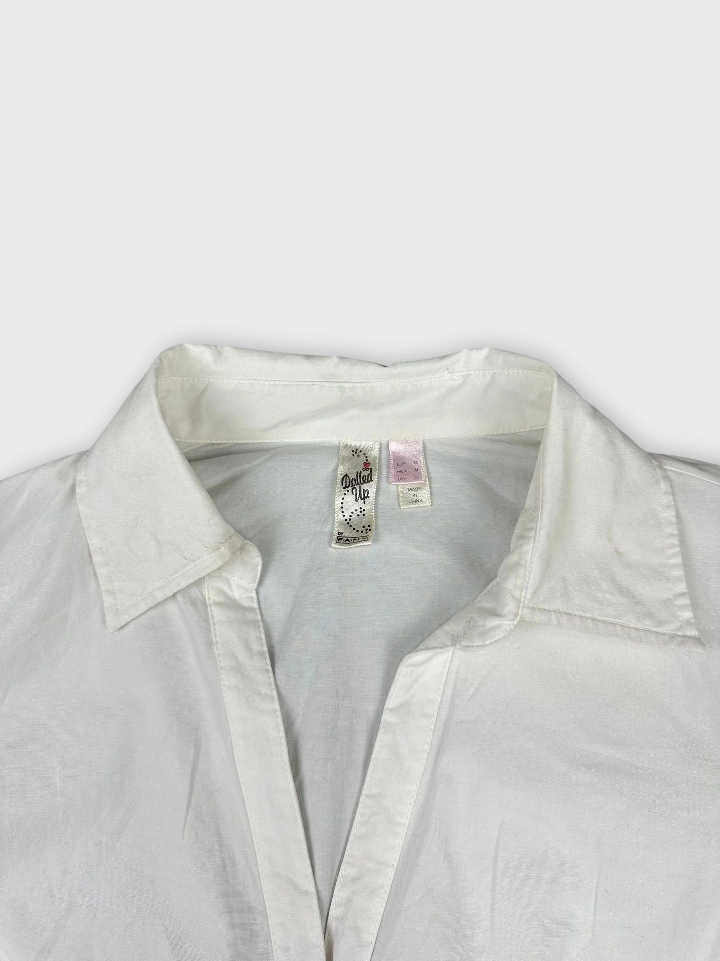 Detail view of a white long sleeve button-up shirt with a classic collar.