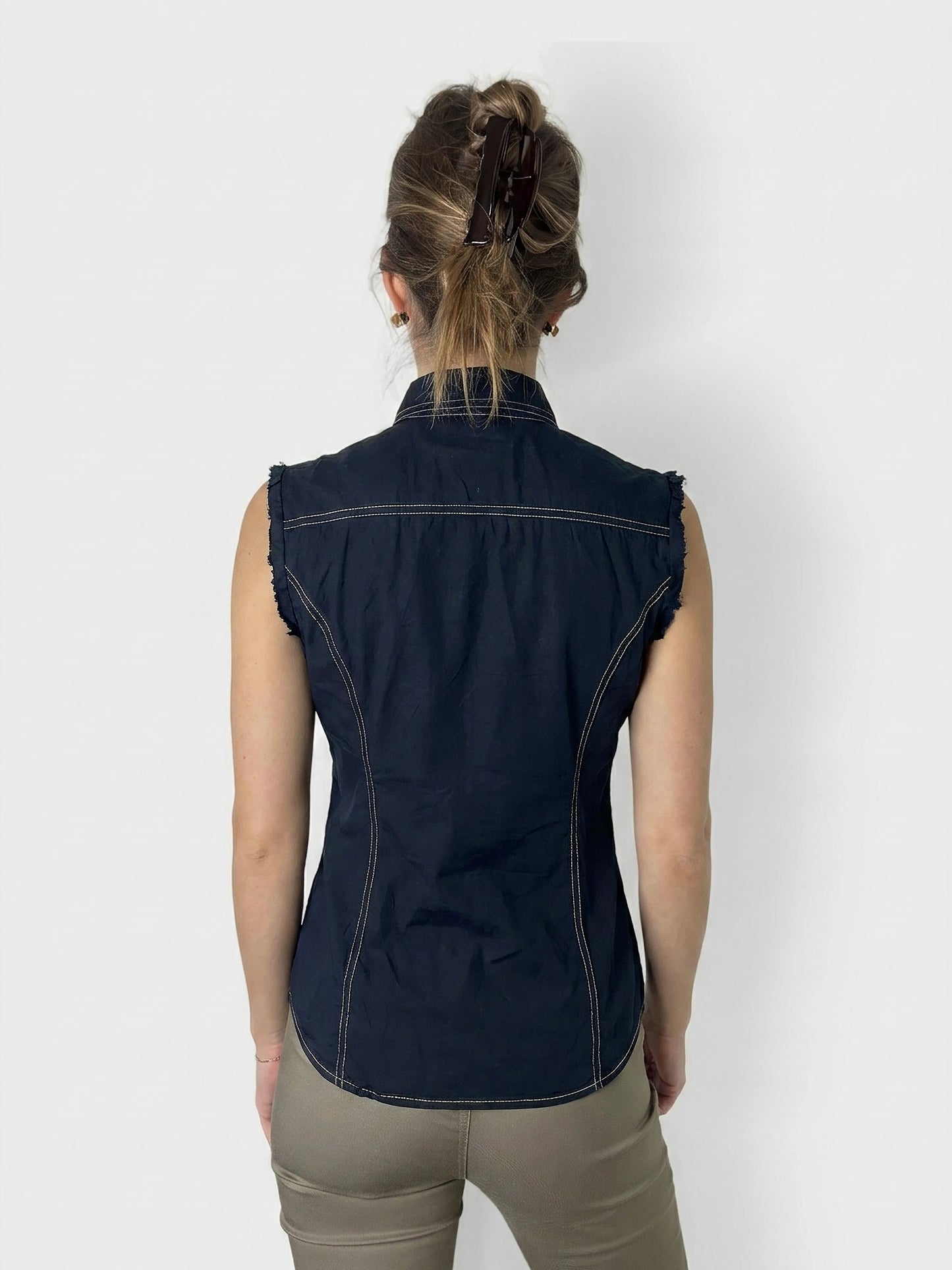 Back view of a classic denim button-up shirt in navy blue with frayed edges.