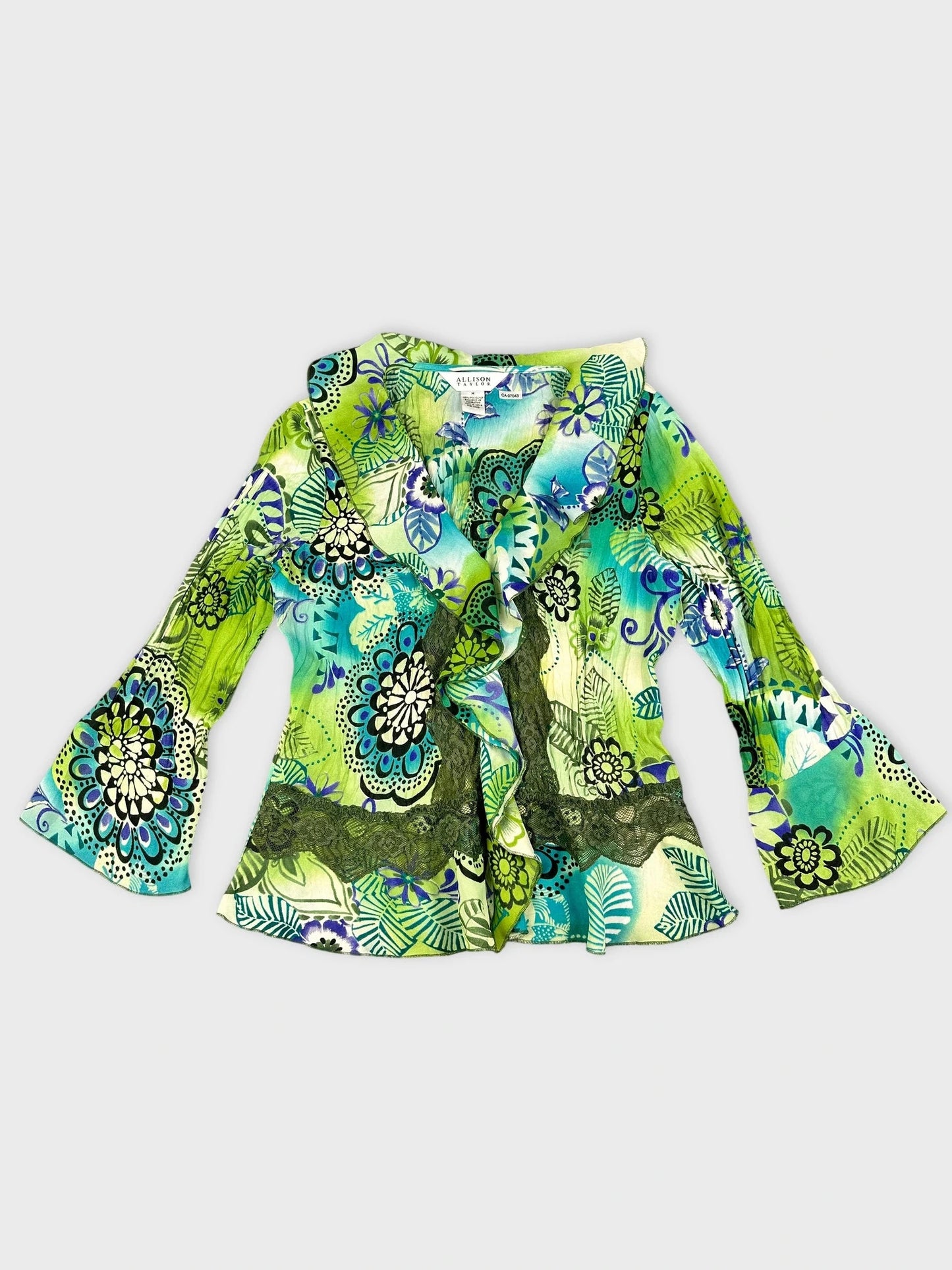 Detail view of a colorful ruffle blouse in green with floral print.