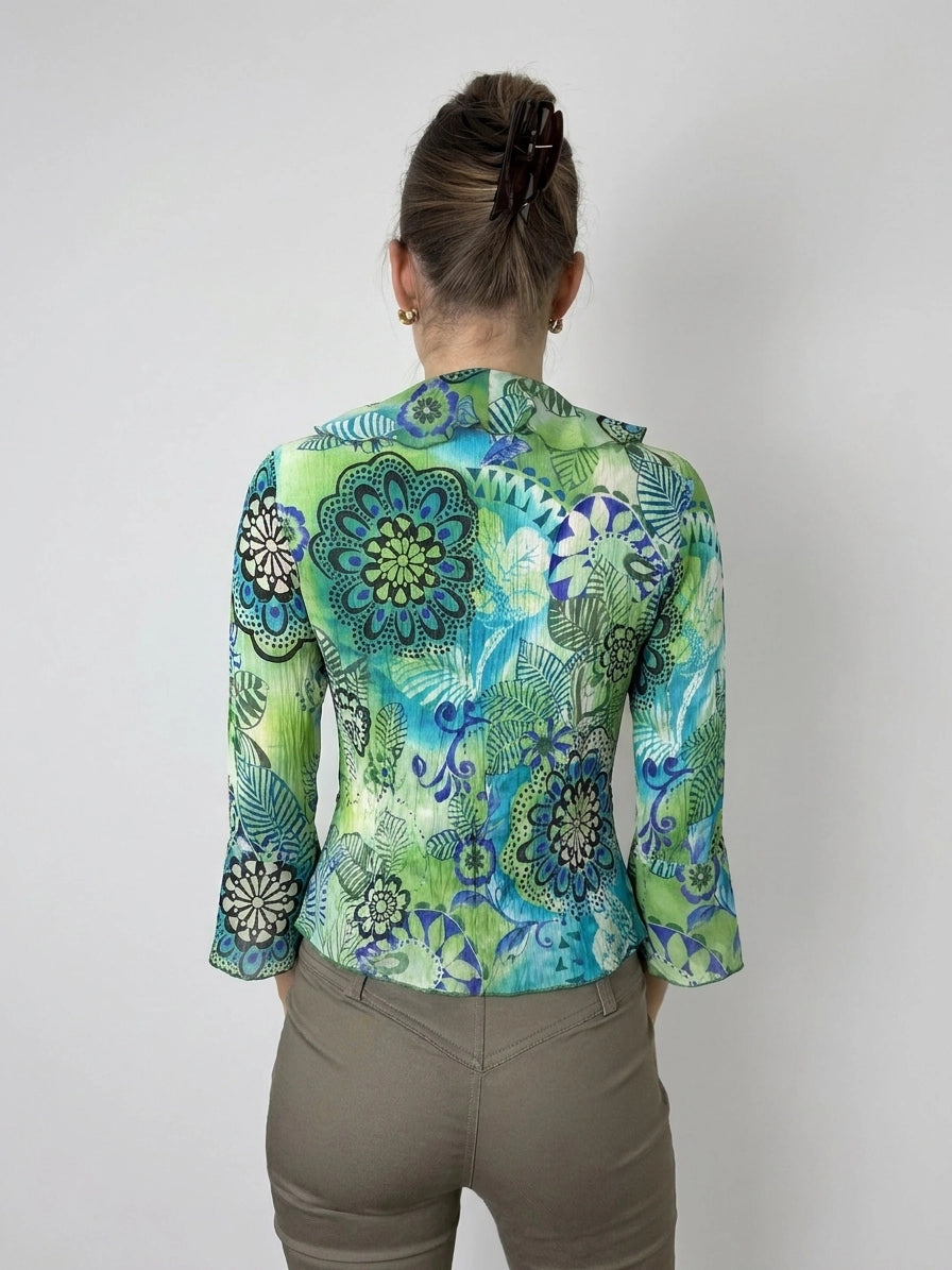Back view of a colorful blouse with floral print and ruffle detail.