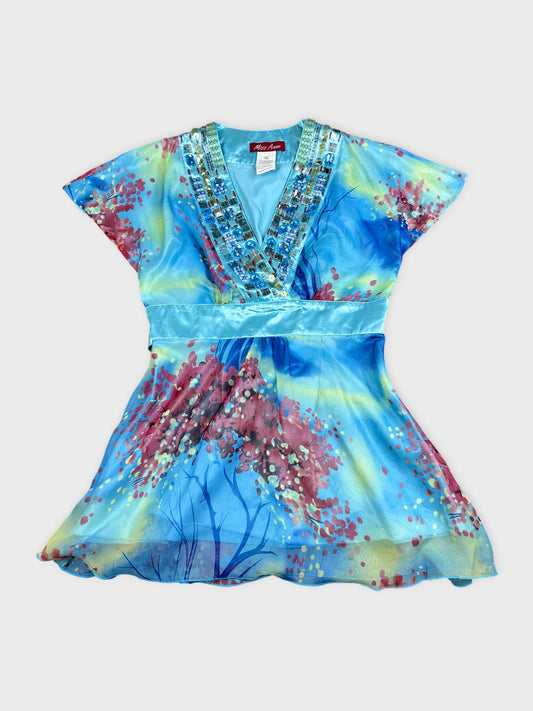 Front view of a colorful blue top featuring floral print and jeweled neckline.