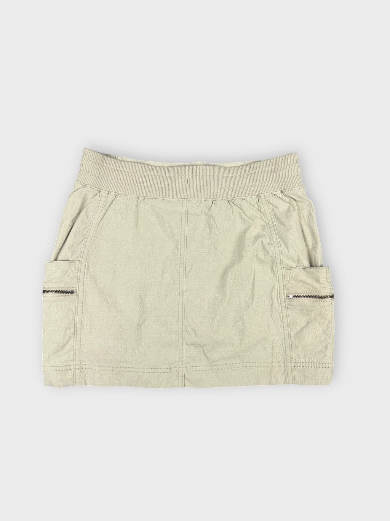 Beige mini skirt back view featuring zip pockets and a casual cut.