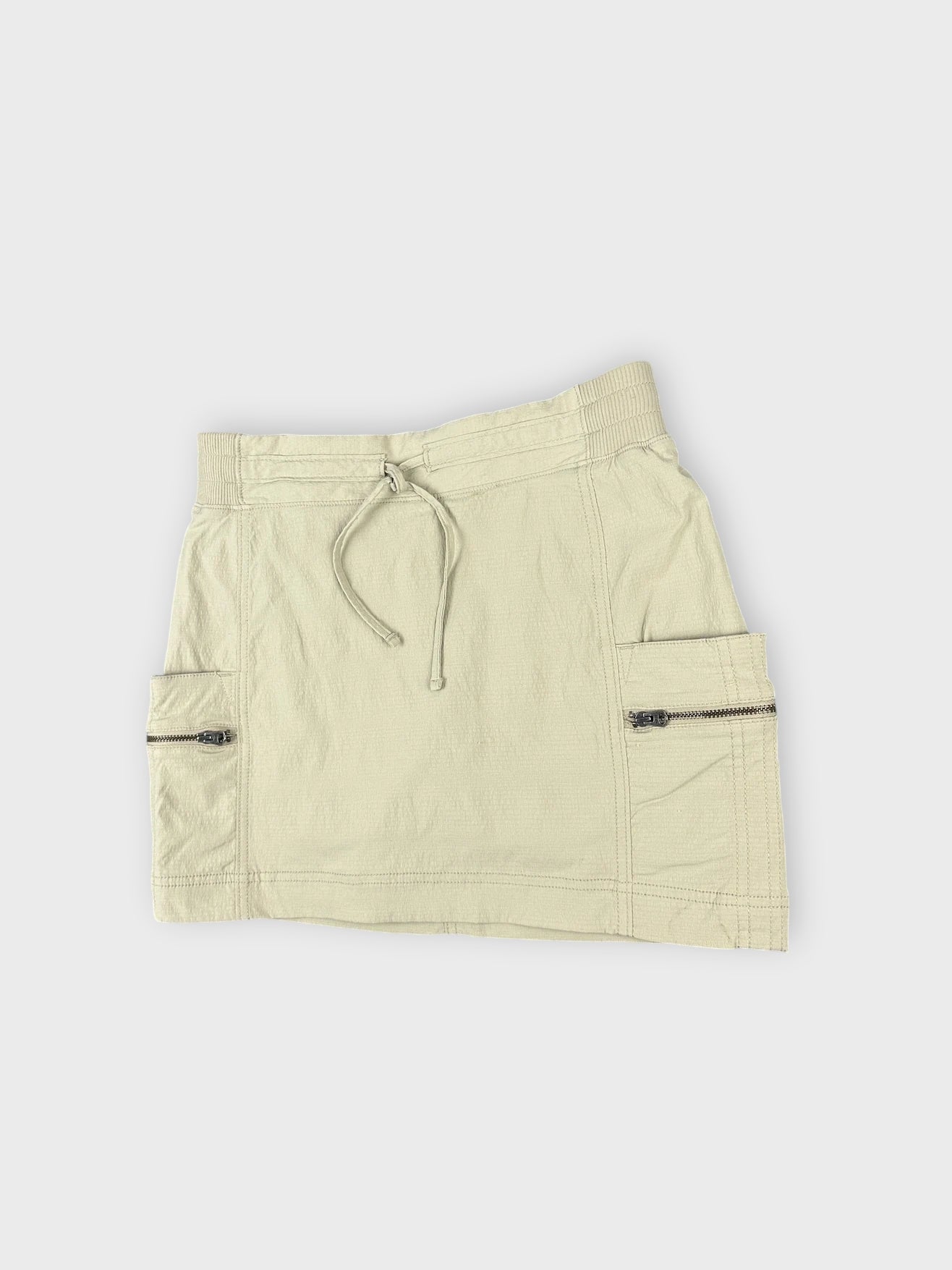 Detail view of a beige mini skirt featuring zip pockets.
