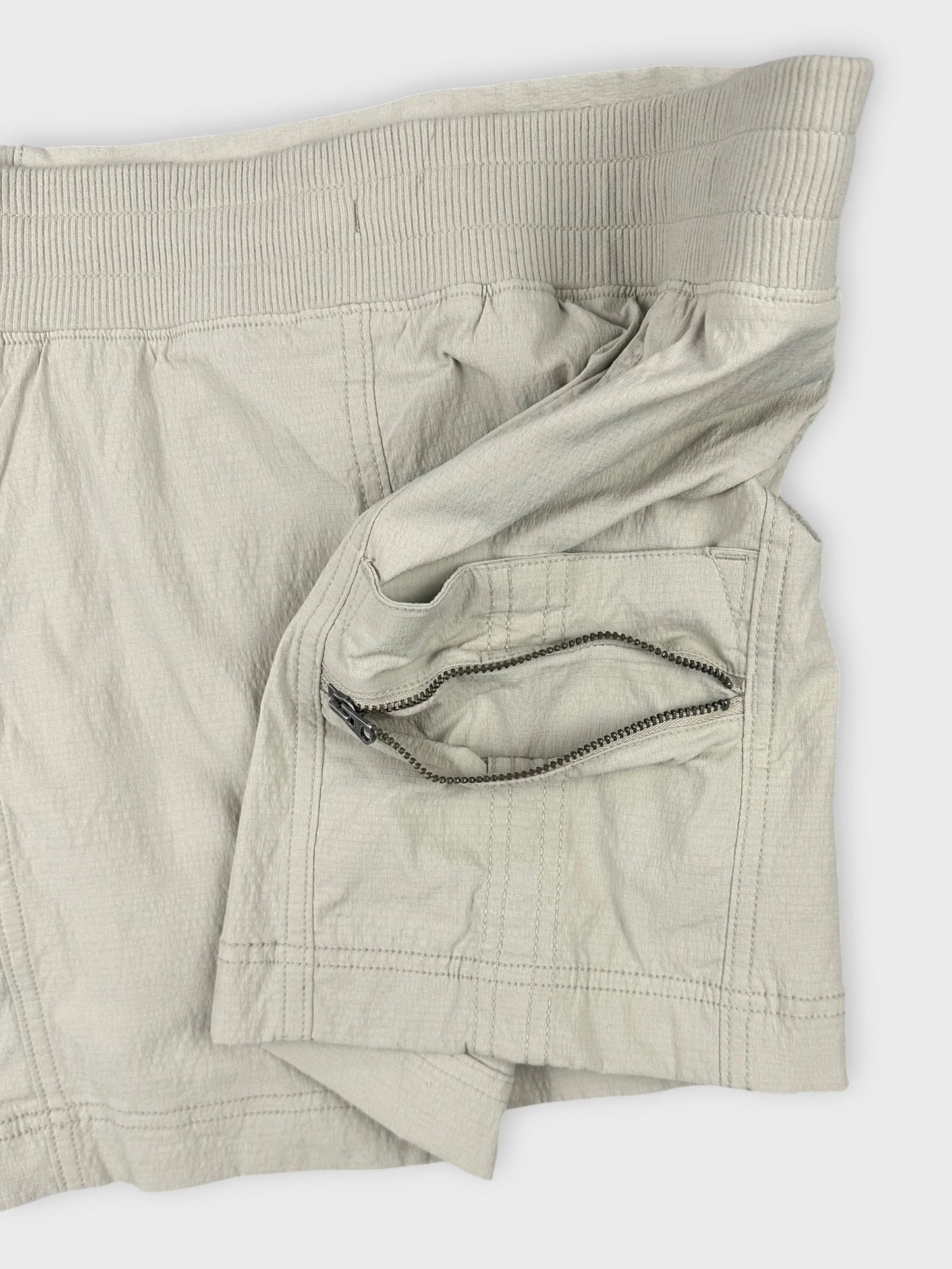 Detail view of a beige mini skirt featuring zip pockets.