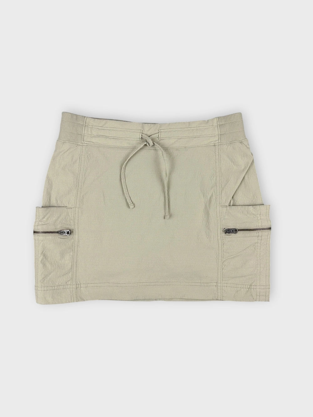 Beige mini skirt with zip pockets in front view.