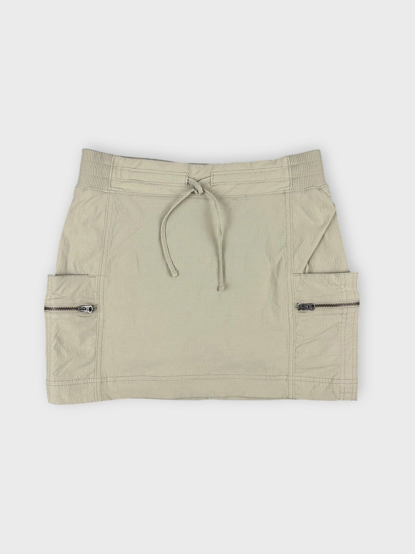 Beige mini skirt with zip pockets in front view.