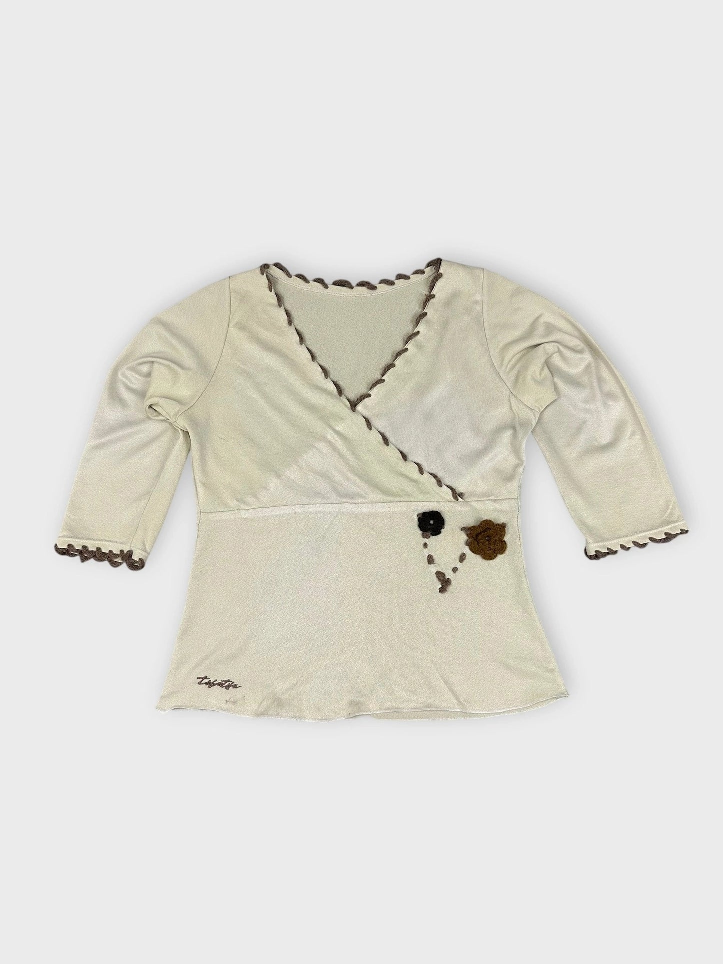 Cream floral wrap top with scalloped edges detail view.