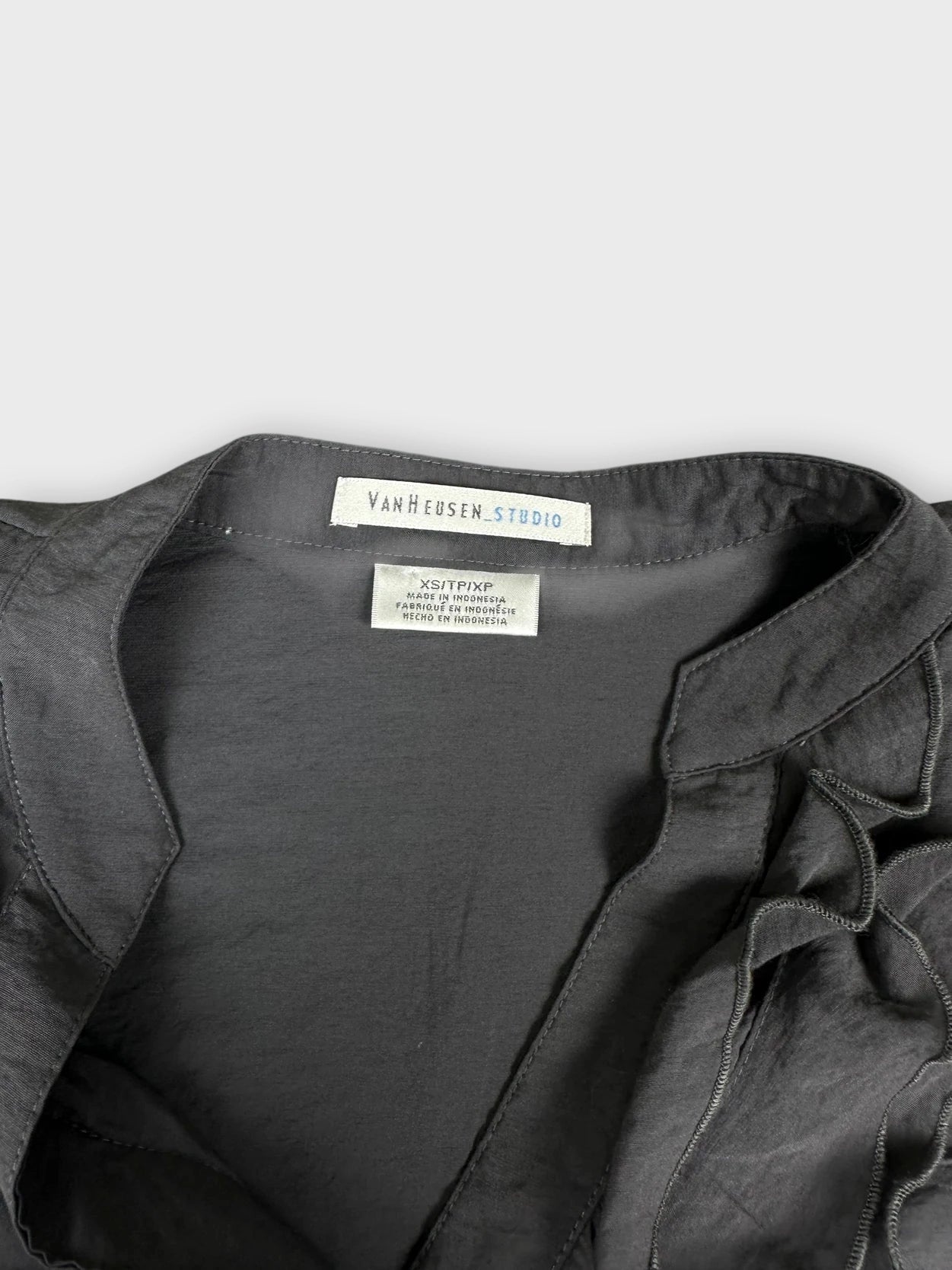 Detail view of a dark gray button-up shirt with ruffled trim.