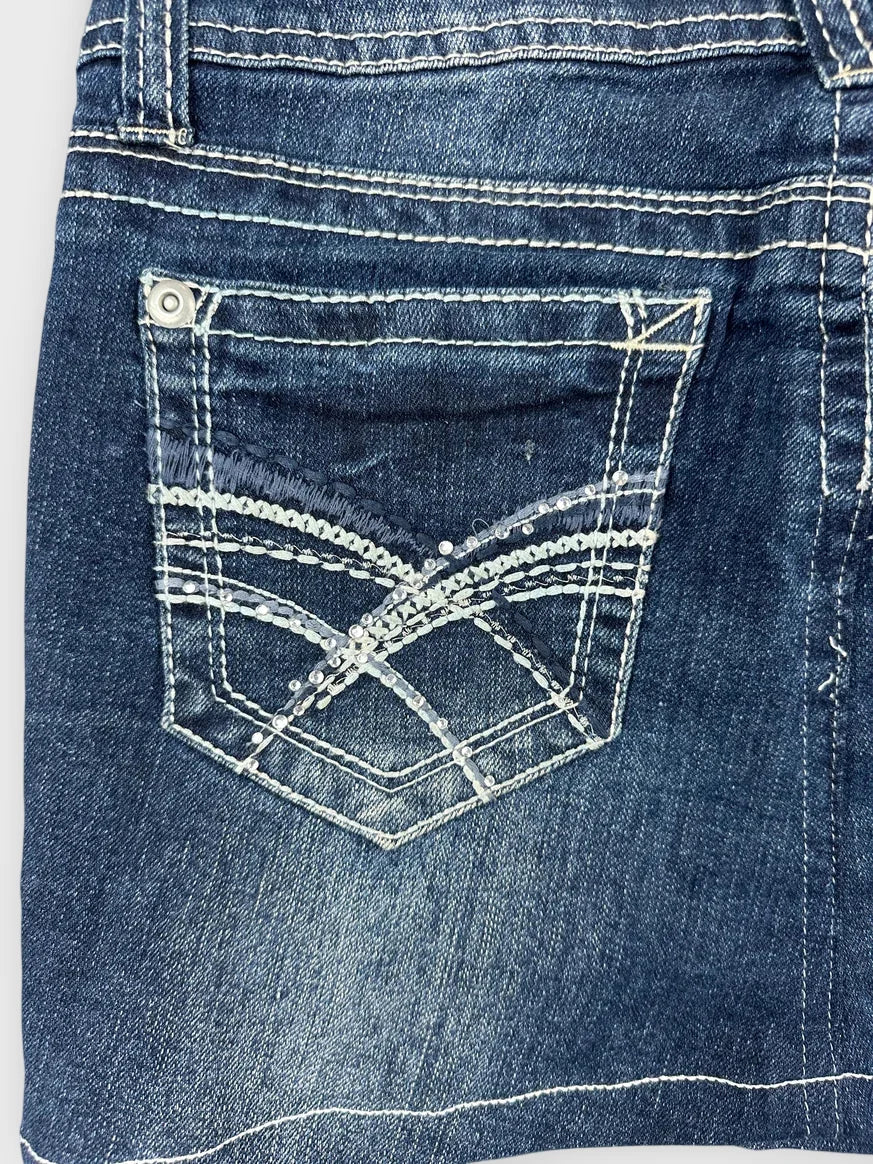 Detail view of dark denim mini skirt featuring back pocket with decorative stitching.