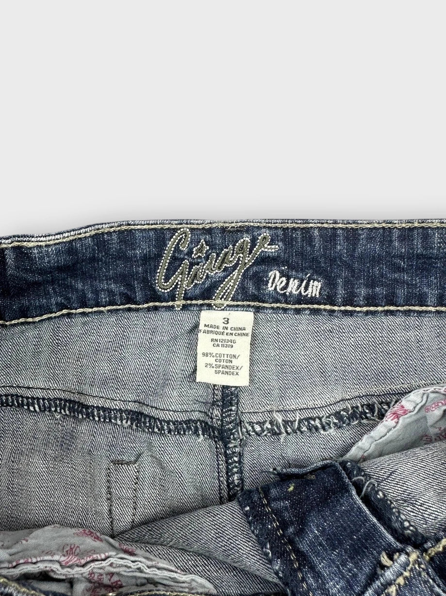 Detail view of blue denim mini skirt with button detail and embroidered label.