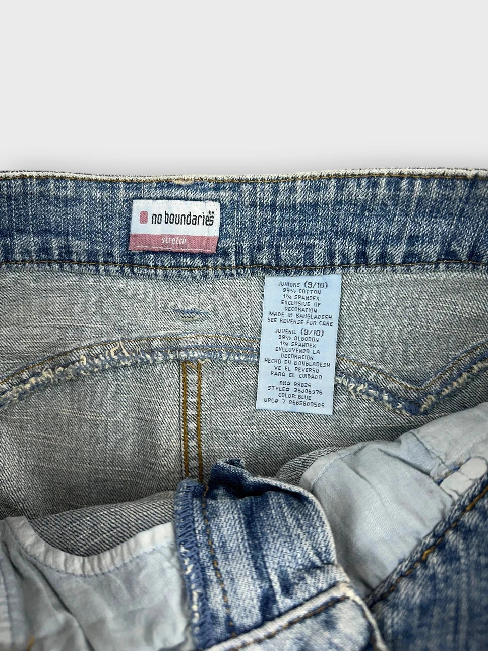 Detail view of denim mini skirt showing light blue fabric and embroidered label.