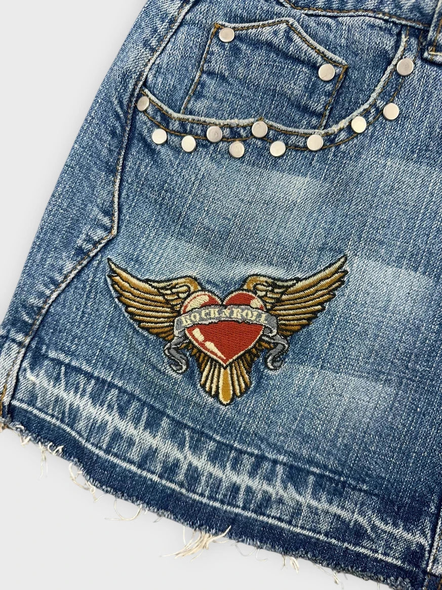 Detail view of a denim mini skirt in light blue with embroidery design.