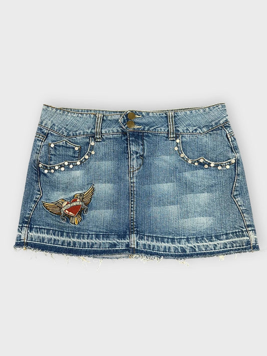 Front view of a denim mini skirt in light blue with embroidered patch.