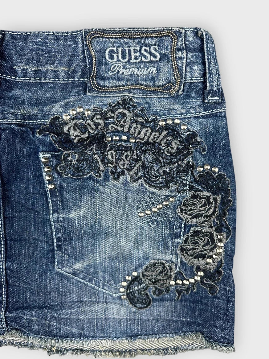 Detail view of a denim mini skirt in dark blue featuring embroidered floral design.