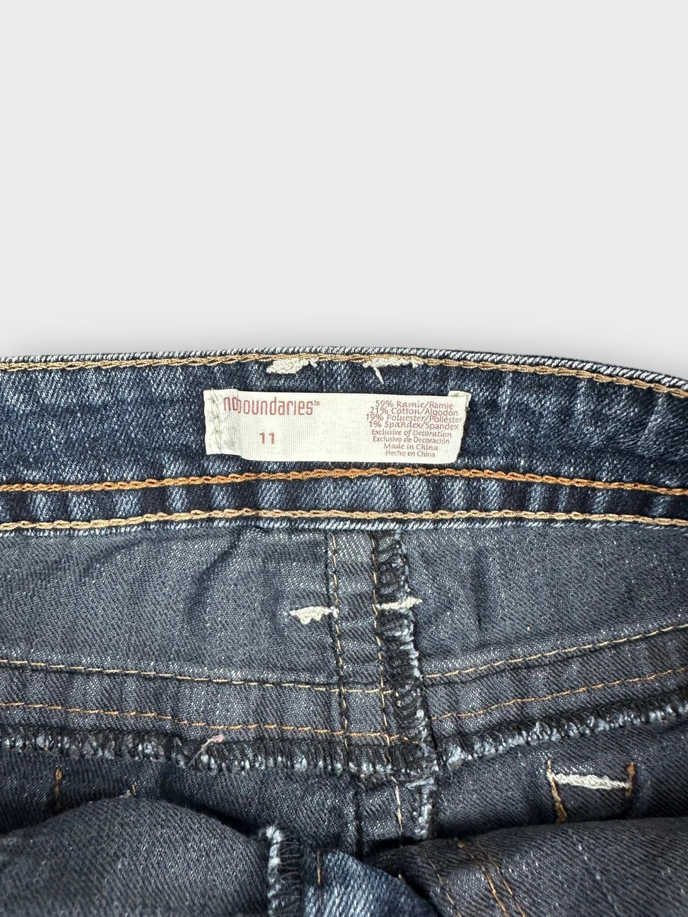 Detail view of a denim mini skirt in dark blue with distressed finish.