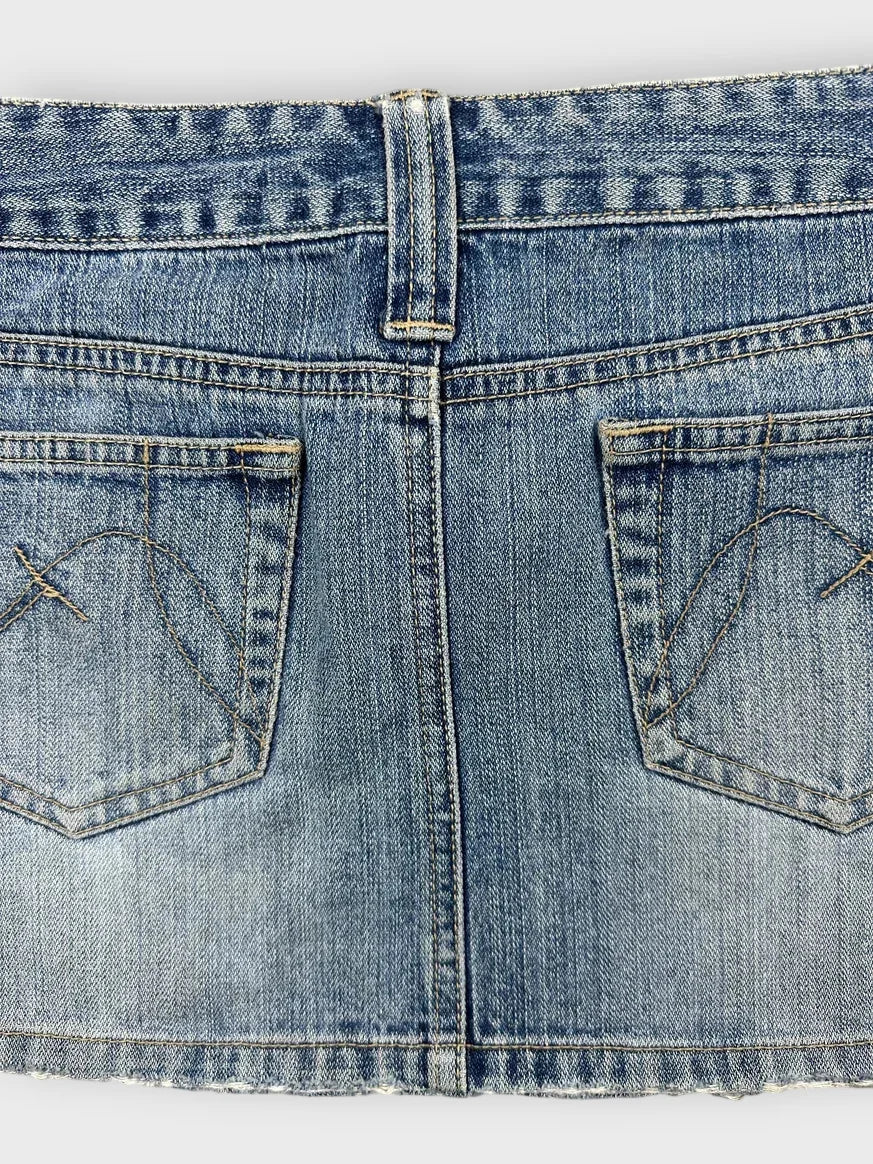 Detail view of a light blue denim mini skirt with a distressed hem.