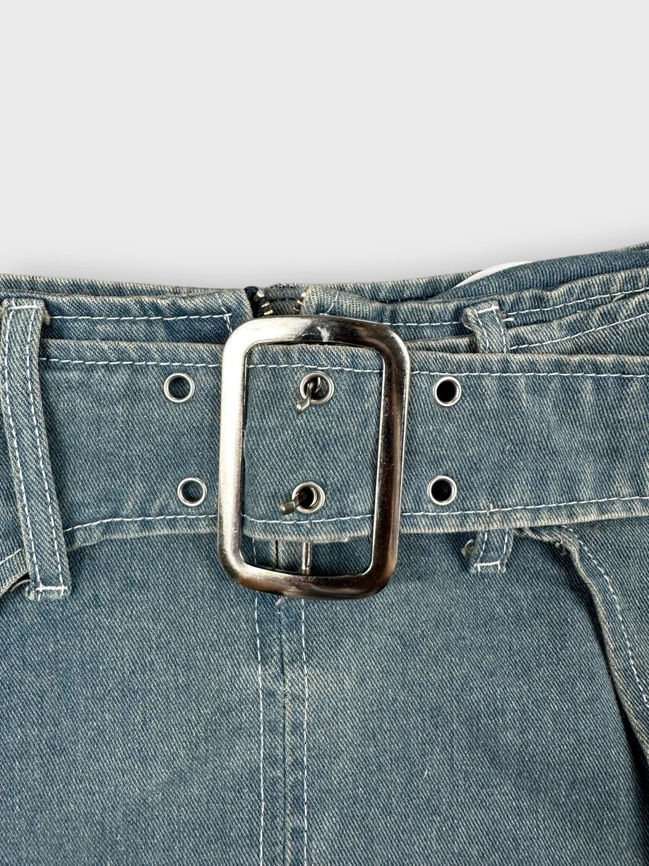 Detail view of a denim mini skirt in light blue with a large silver buckle.