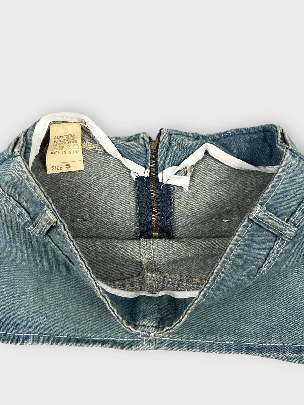 Detail view of a blue denim mini skirt featuring a statement buckle.