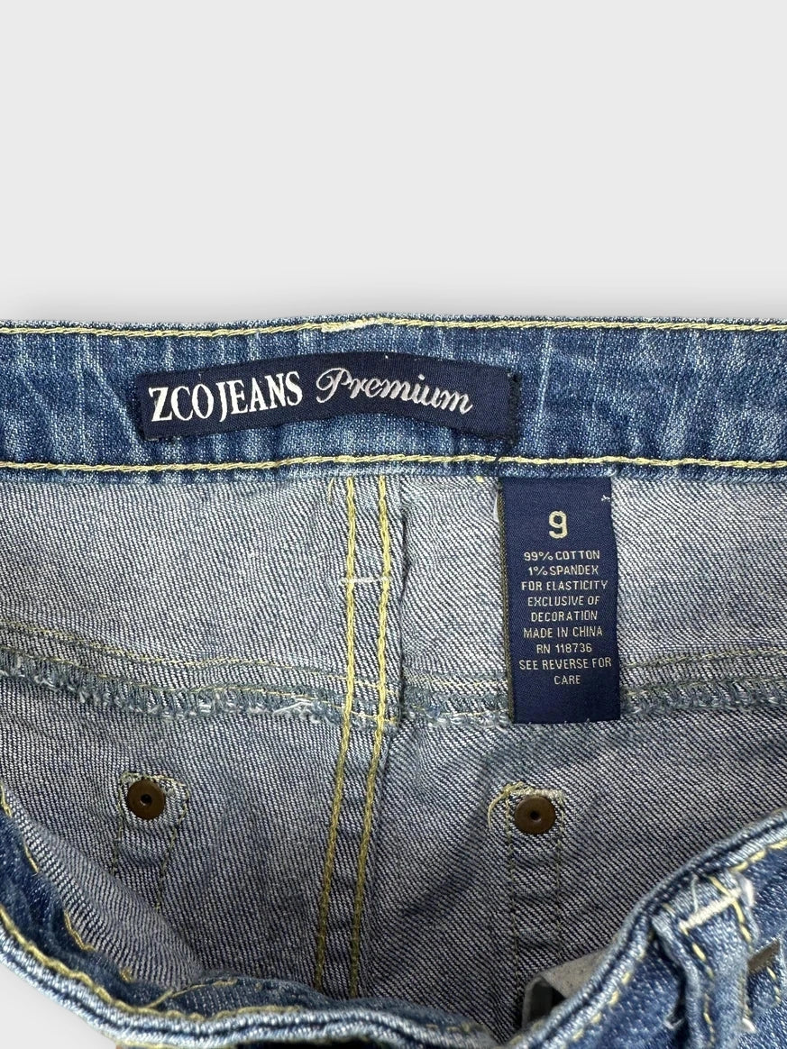 Detail view of blue distressed denim mini shorts with frayed hem.
