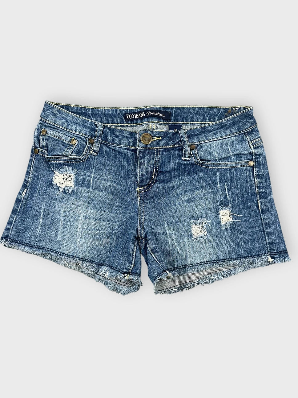 Distressed denim mini shorts in blue front view with frayed hem details.