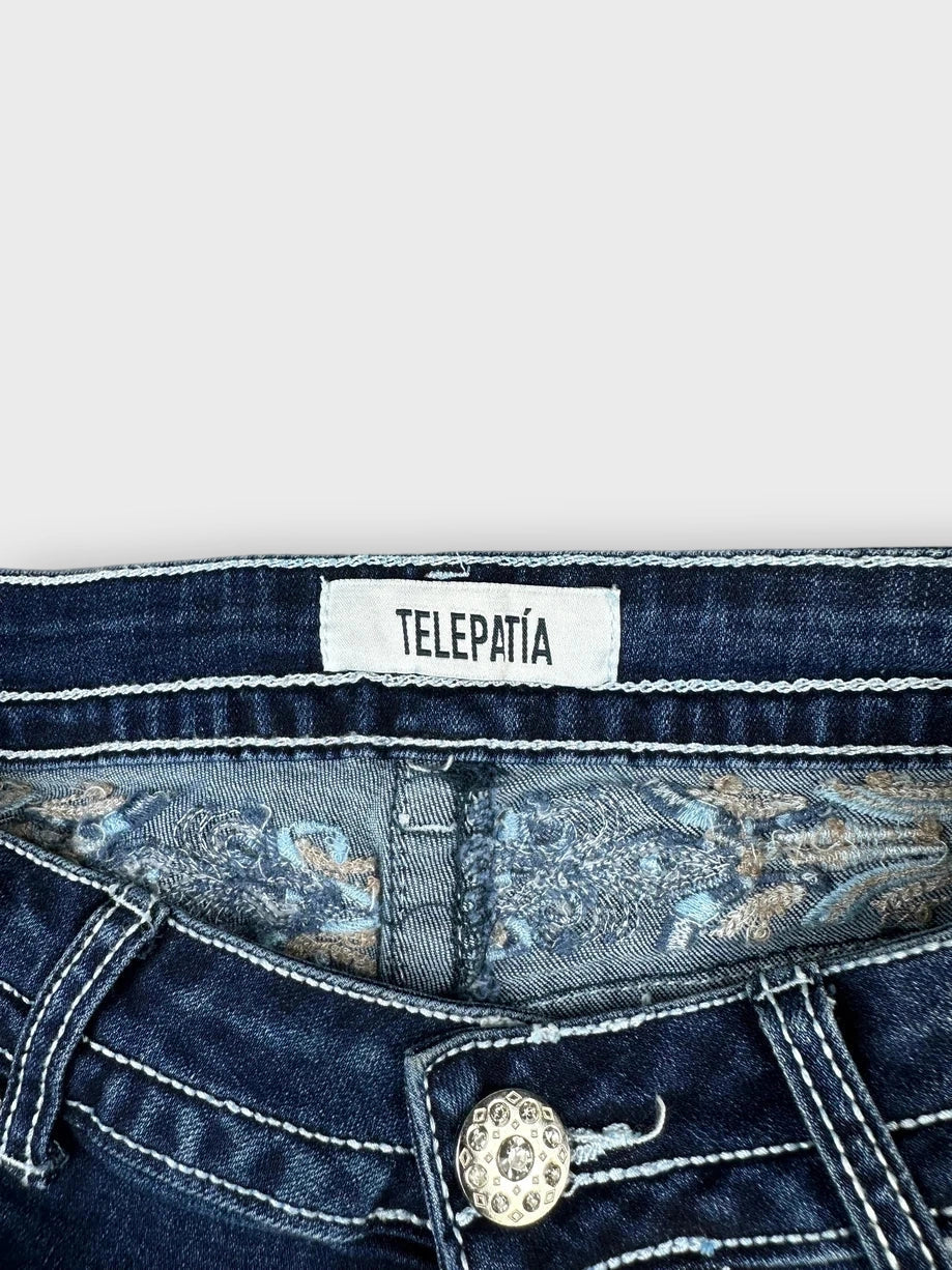 Detail view of dark denim mini shorts with embellished button and floral lining.